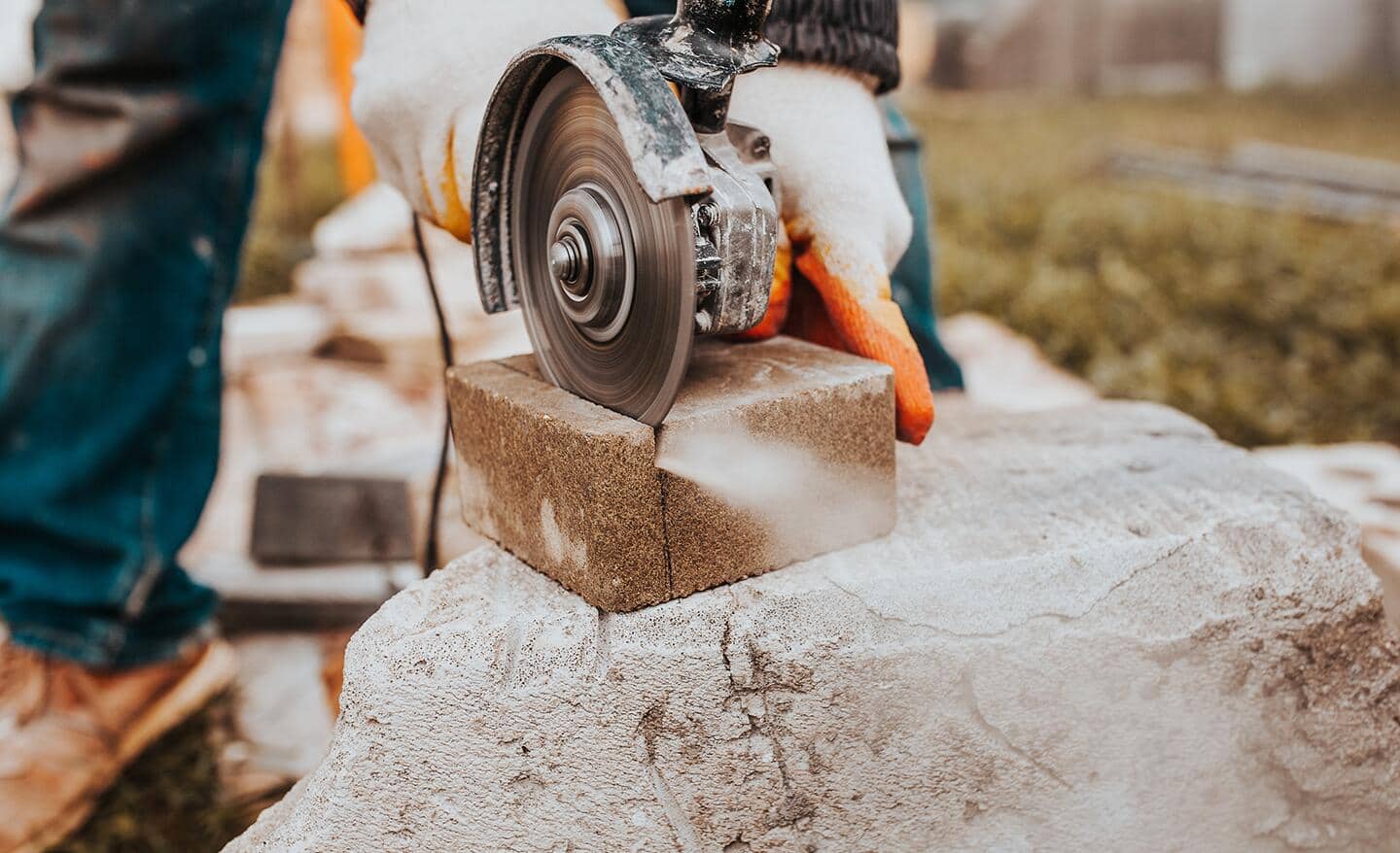 A retaining wall block is cut with an angle grinder and cutting wheel.