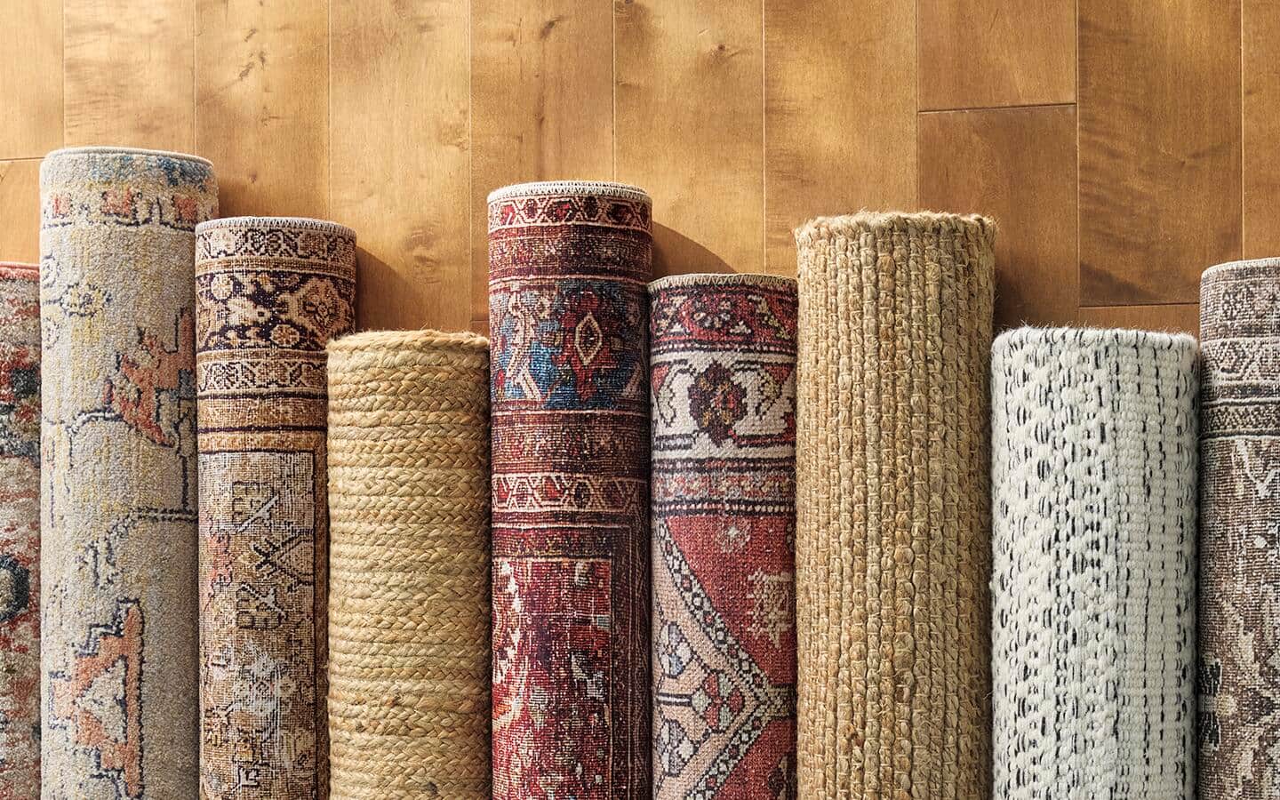 Several rolled rugs placed on a wood floor in a row.
