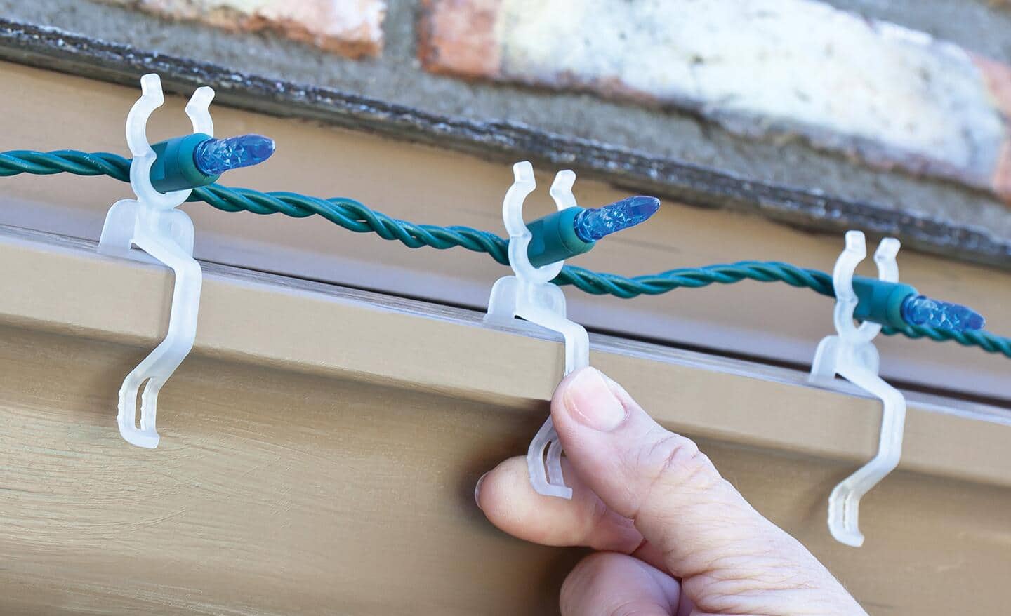 A person securing Christmas lights with plastic hooks and clips. A person securing Christmas lights with plastic hooks and clips.