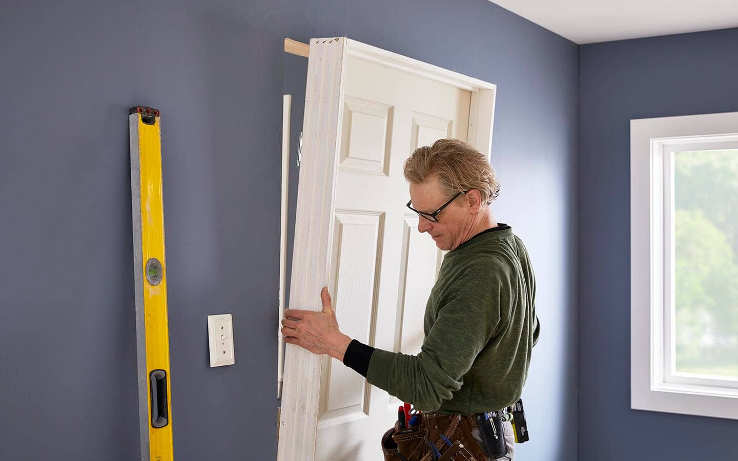 A person fitting a prehung interior door into an opening.