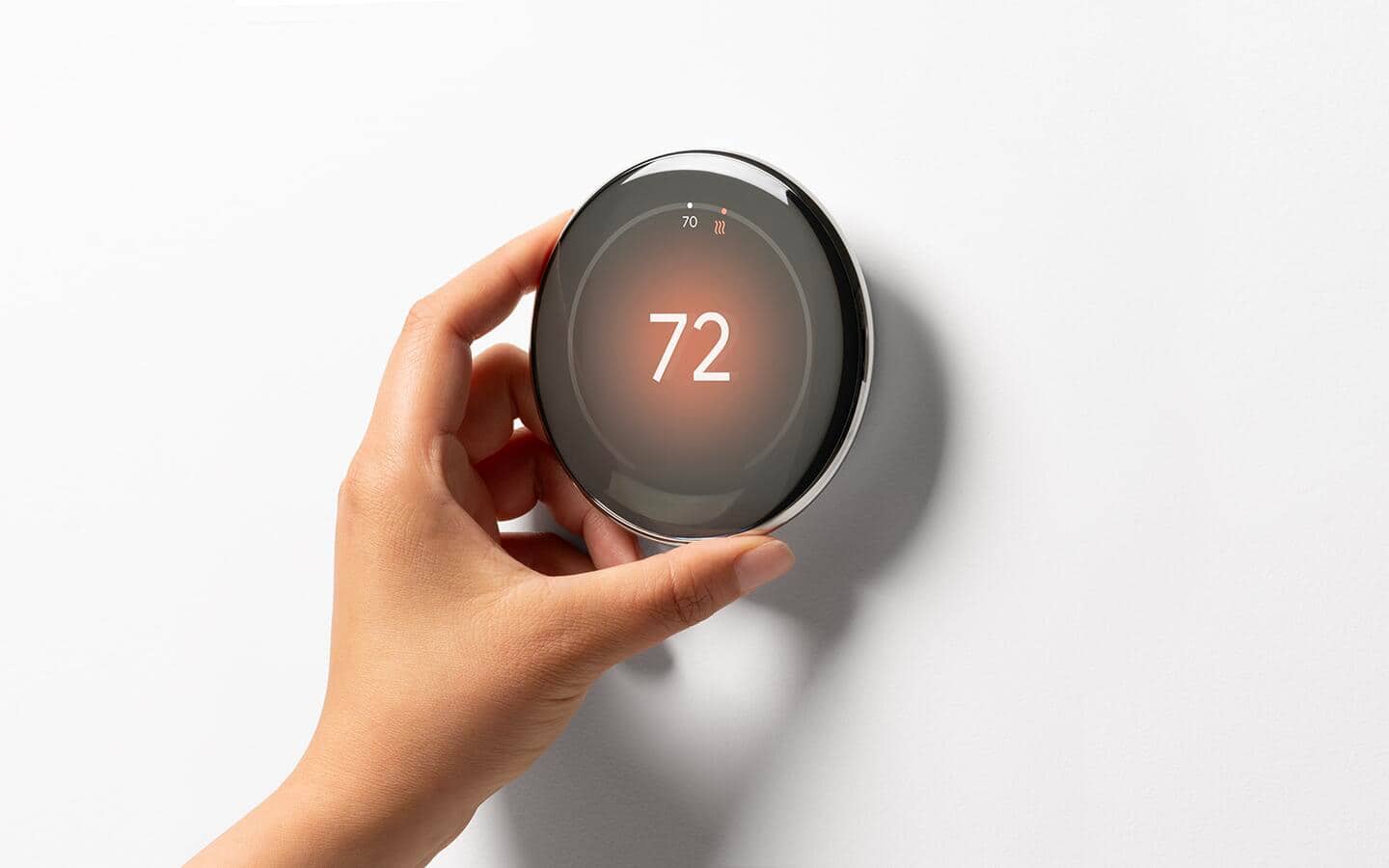 A person adjusts a smart thermostat.