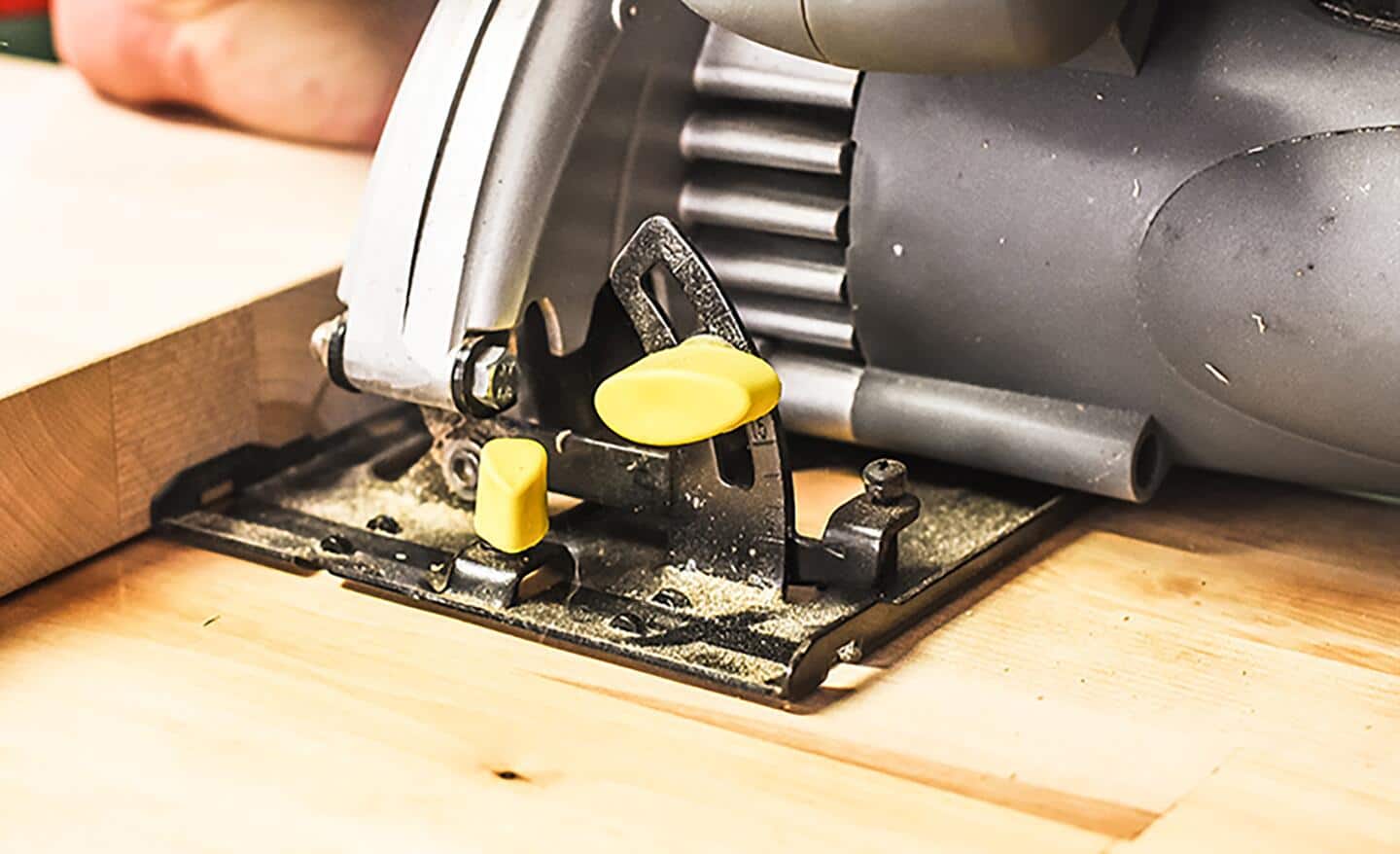 A person trims a section of butcher block with a saw.