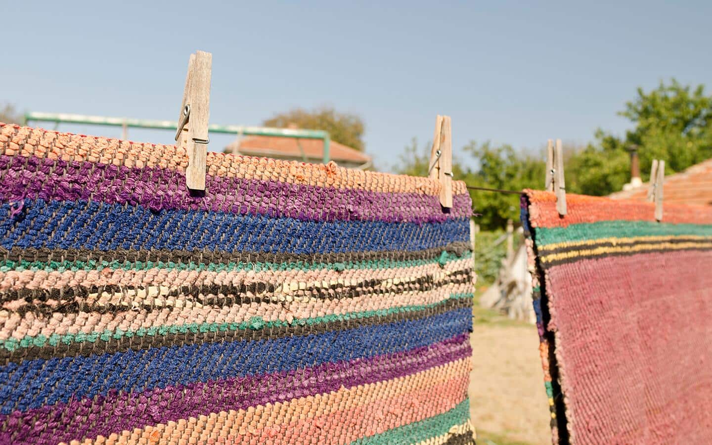 Outdoor rugs hanging to dry on a clothesline.