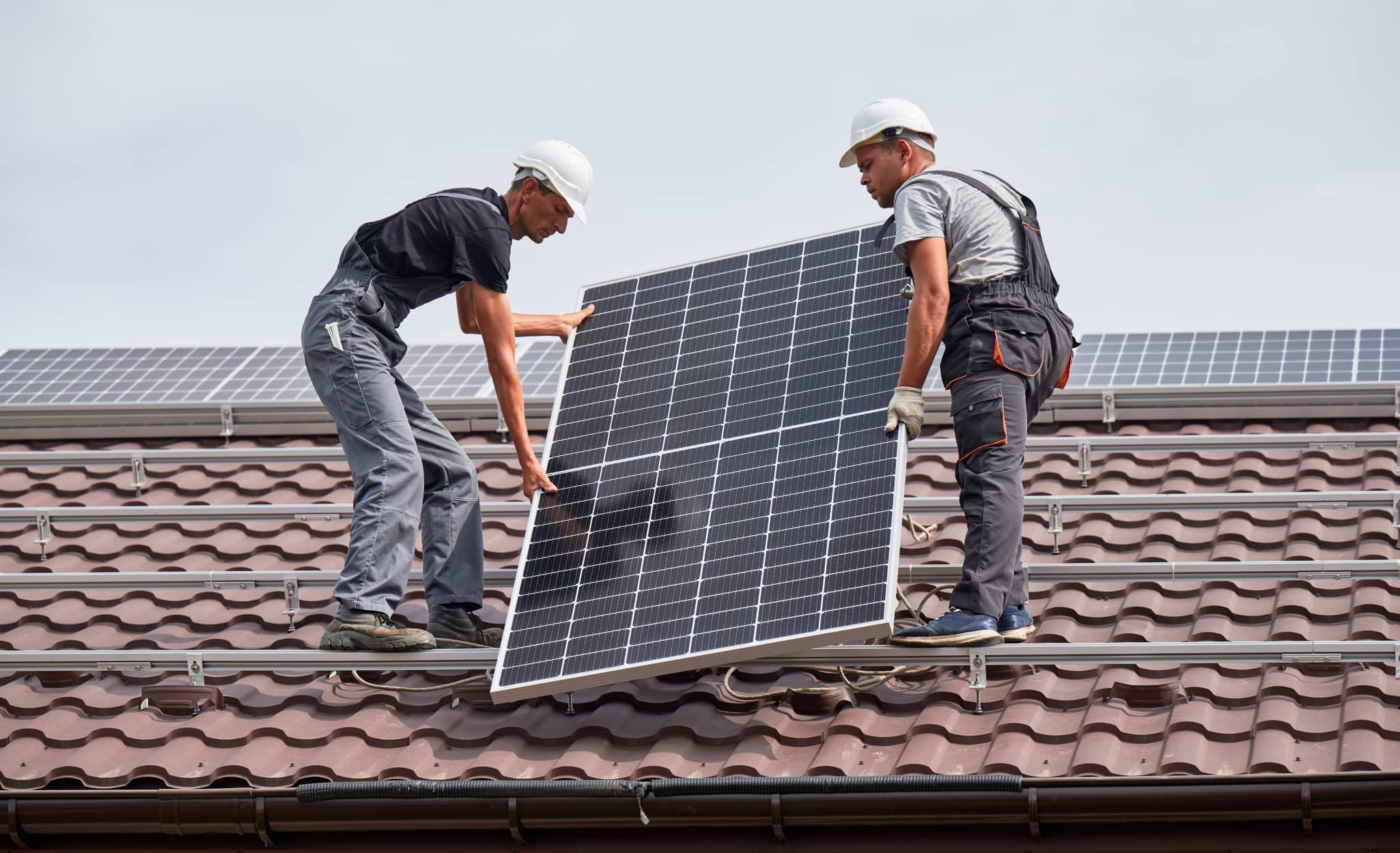 Pros install a solar panel on a roof. Pros install a solar panel on a roof.