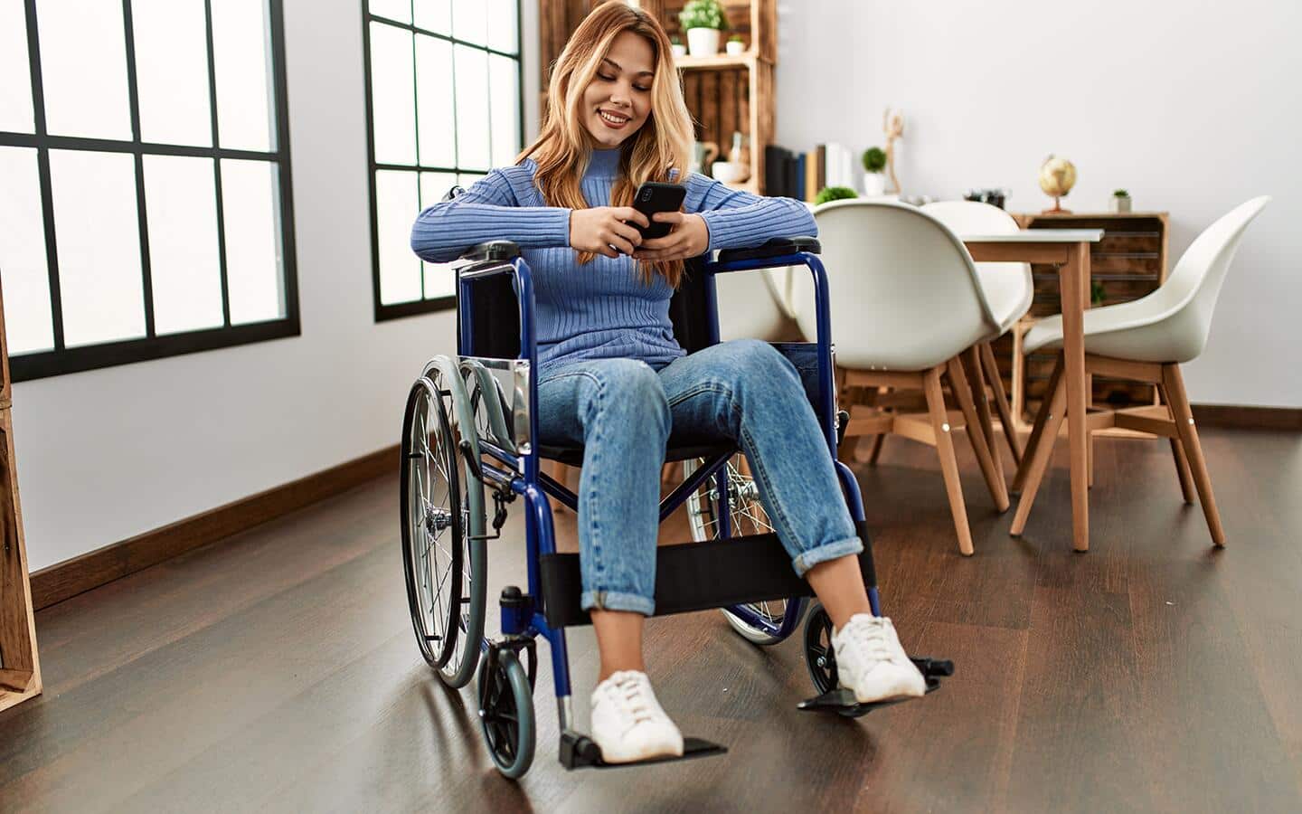 A woman in a wheelchair uses a smartphone. A woman in a wheelchair uses a smartphone.
