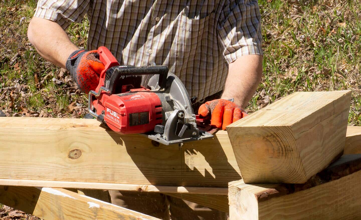 A man uses a circular saw to cut corner braces from 6x6 pressure treated posts.