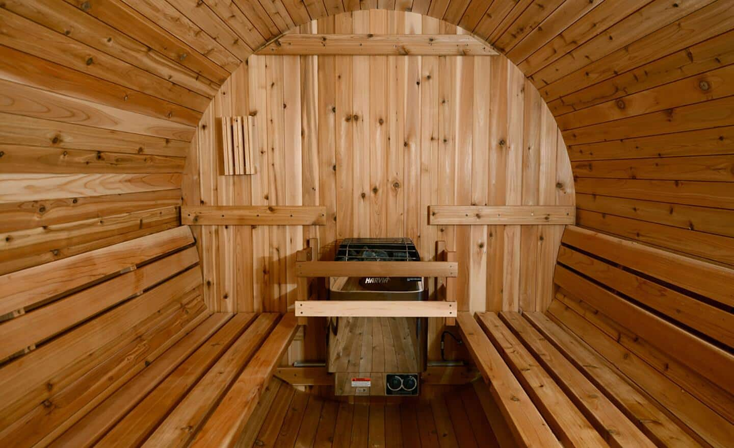 The wooden inside of a barrel sauna with bench seating.