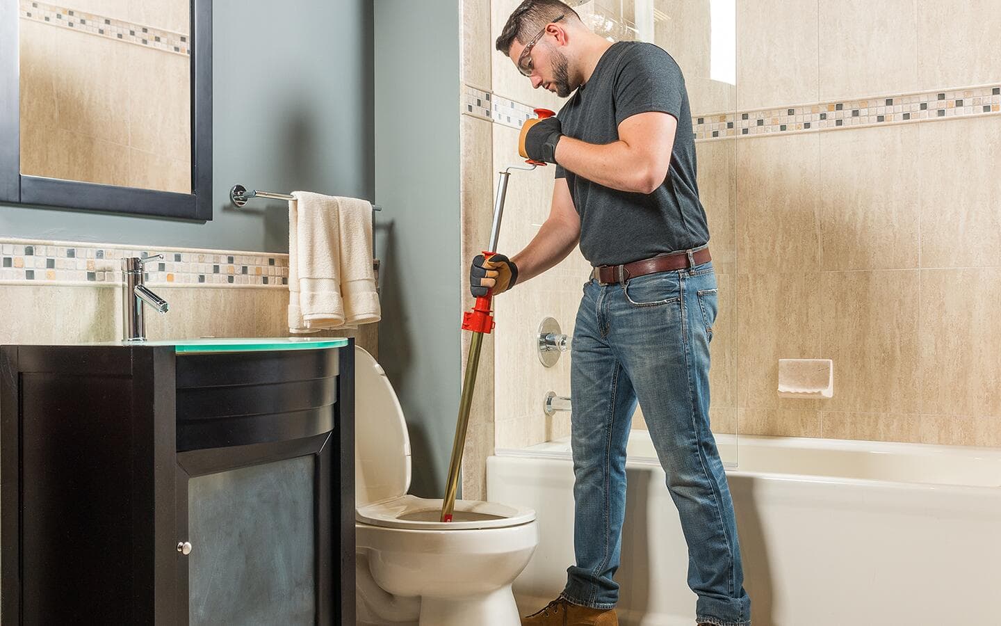 A person uses an auger in a toilet. A person uses an auger in a toilet.