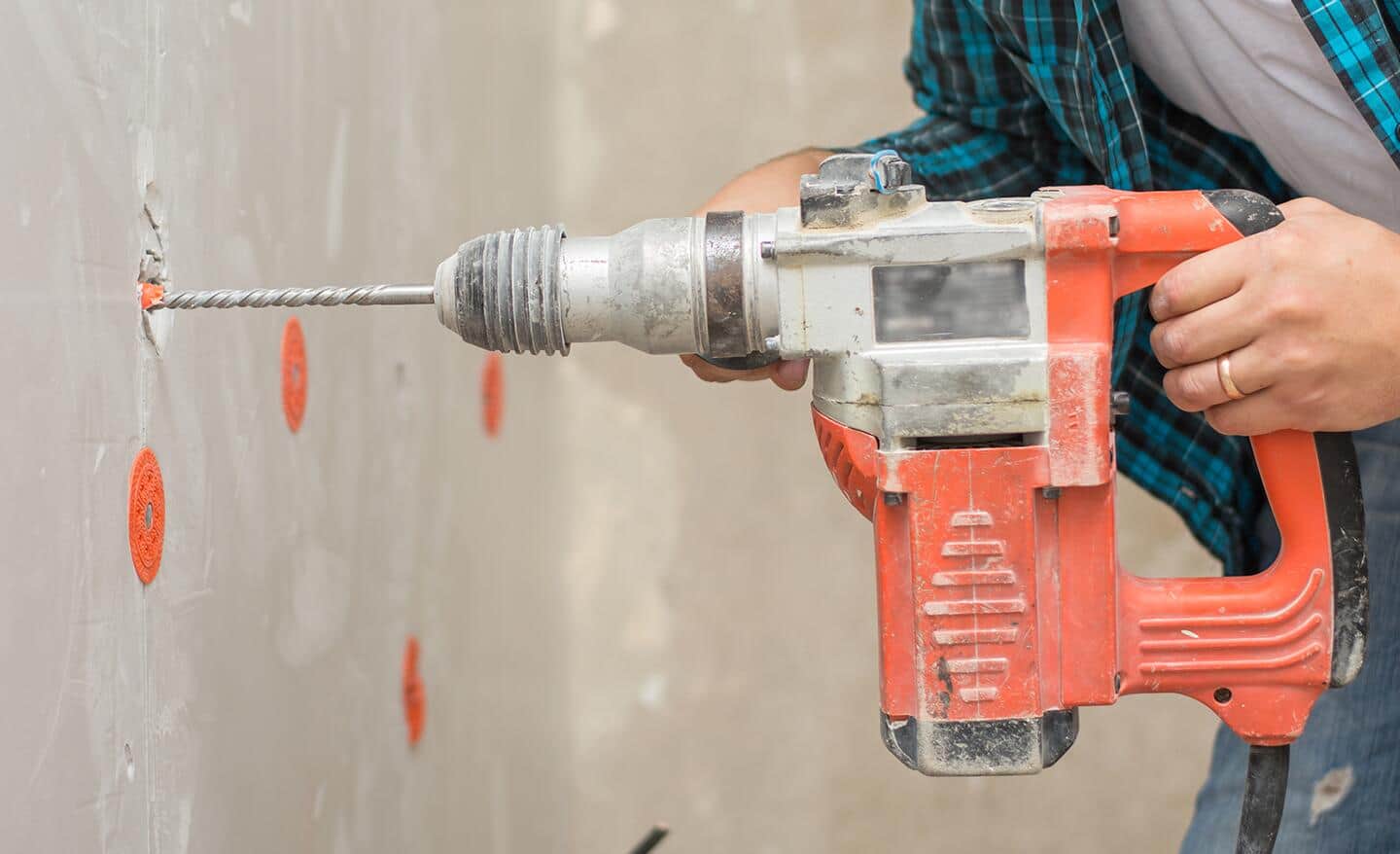 A person drilling into unfinished drywall.