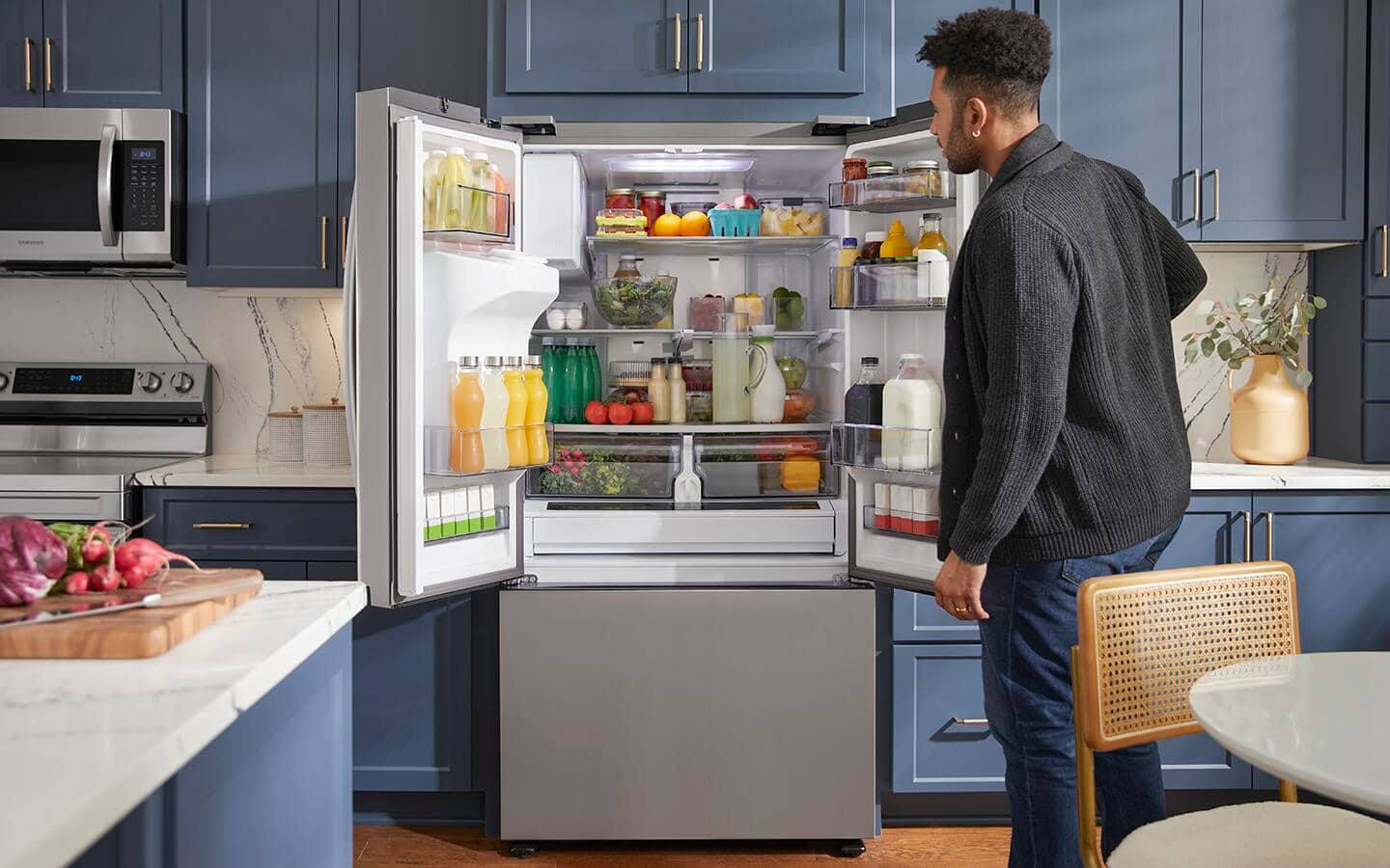 A man checking food in an open smart refrigerator with freezer. A man checking food in an open smart refrigerator with freezer.