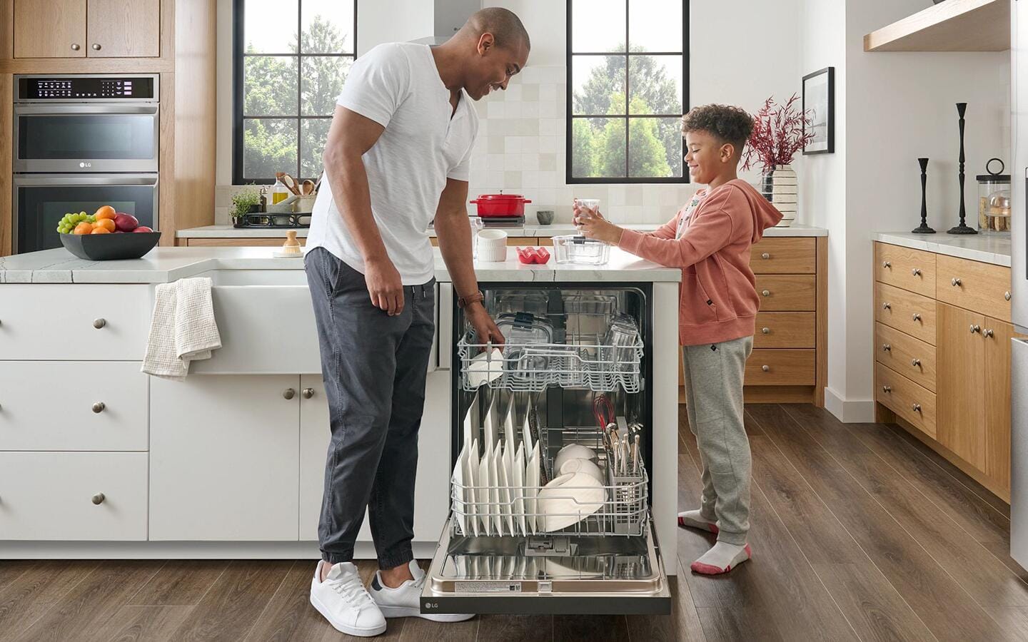 A man and boy load a dishwasher together.