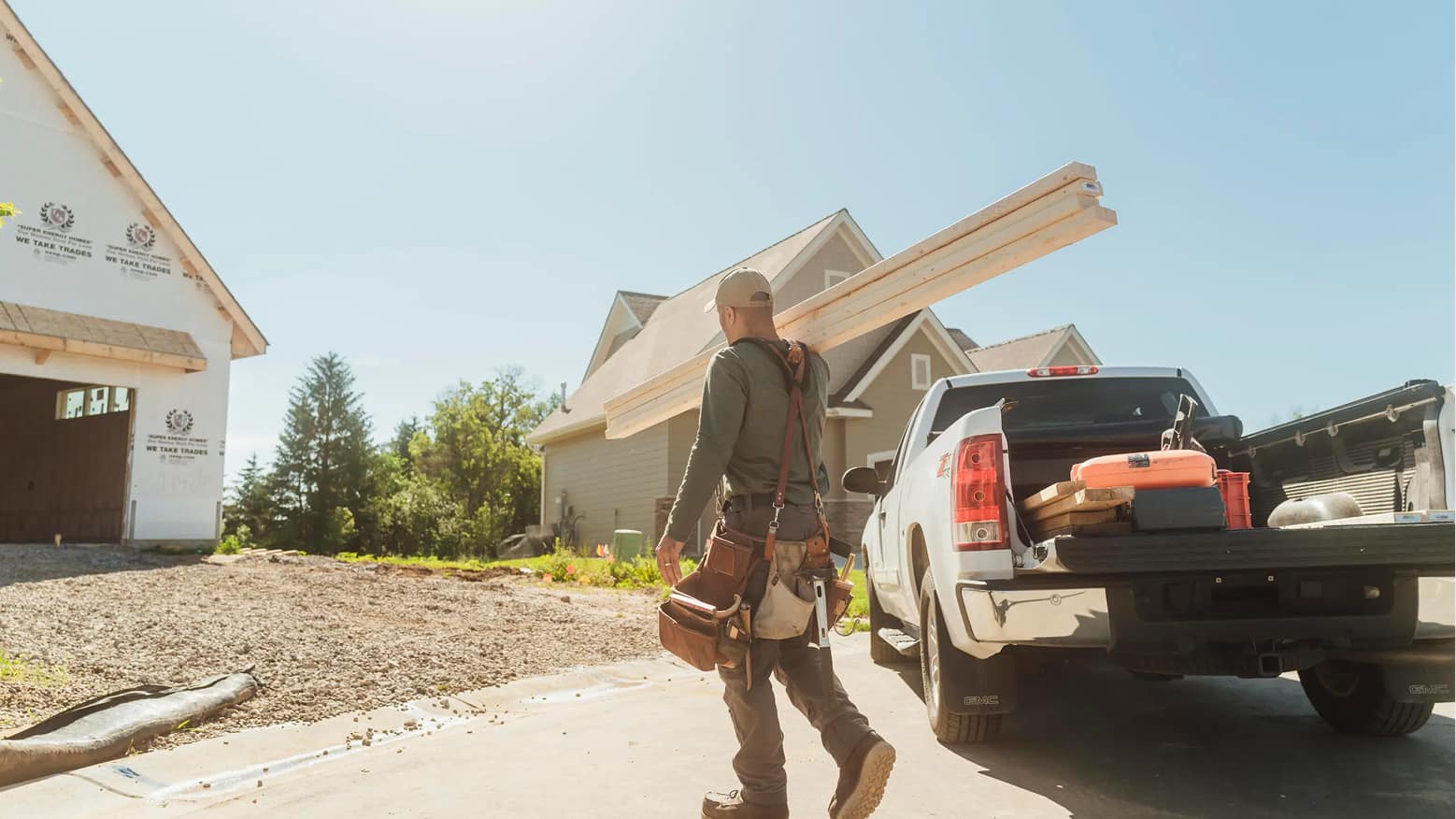 A carpenter carries boards at a home-building job site.