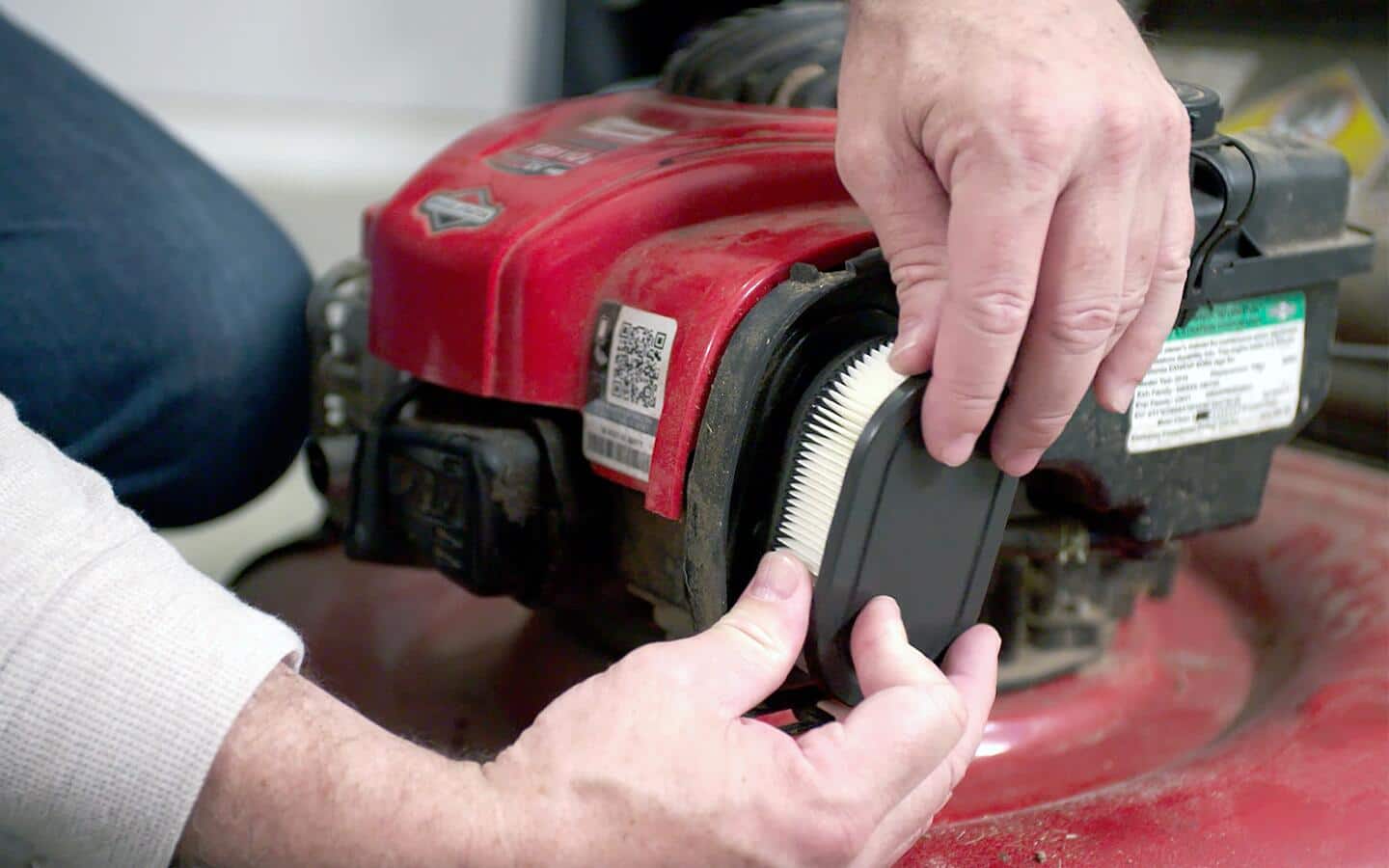 A person replaces a lawn mower's air filter. A person replaces a lawn mower's air filter.