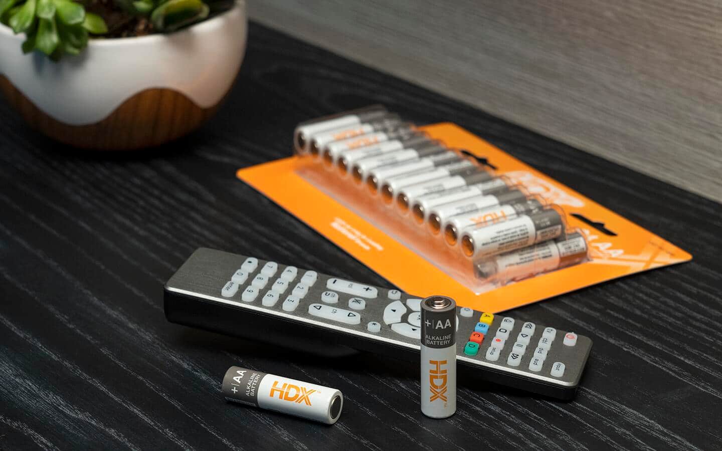 A package of AA alkaline batteries next to a remote control.