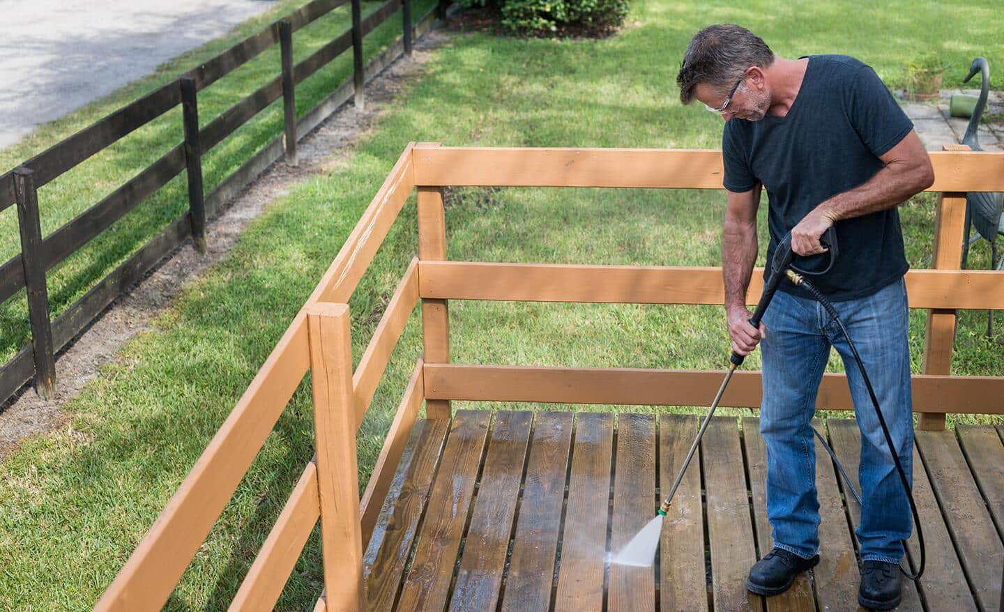 A man pressure washes his deck.