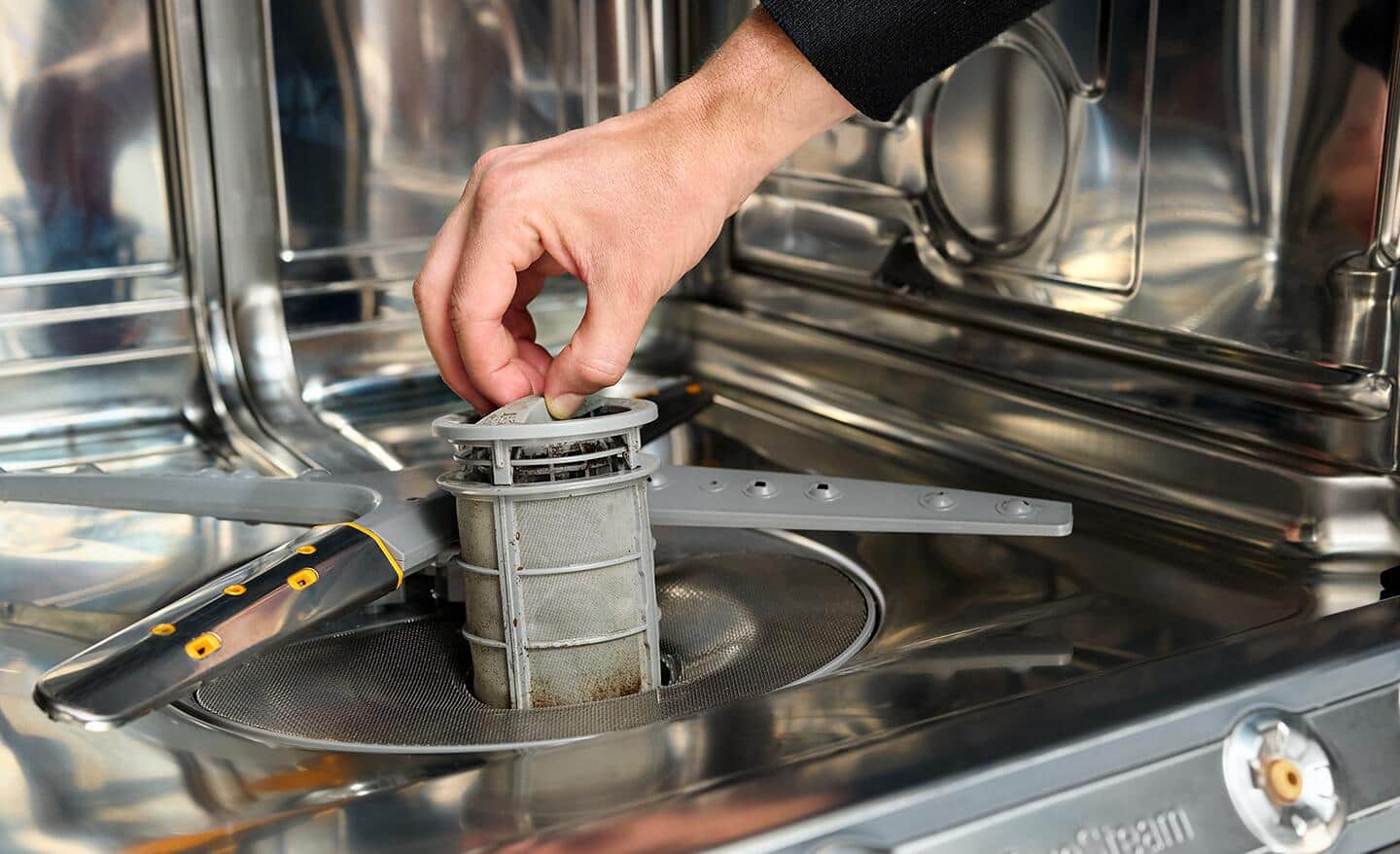 A person removing the filter from a dishwasher.