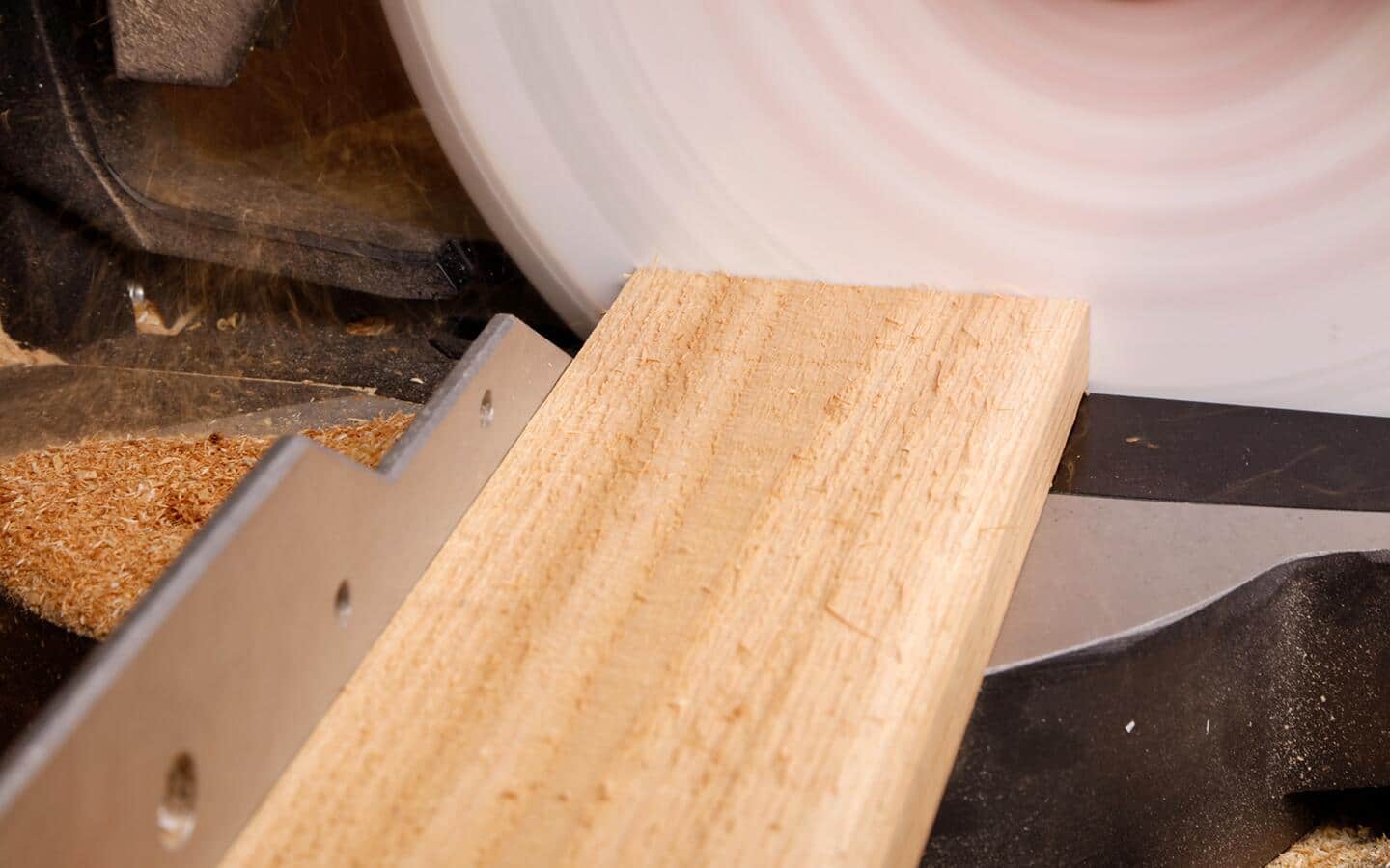 A cedar board being fed into a table saw.
