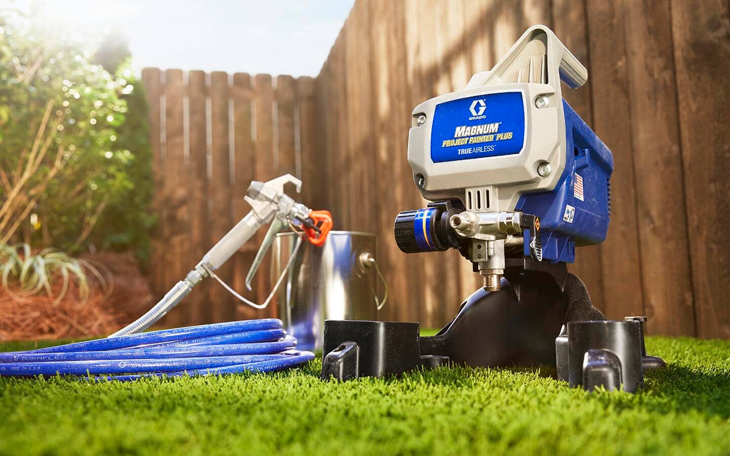 An airless paint sprayer and its hose attachment sitting in grass.