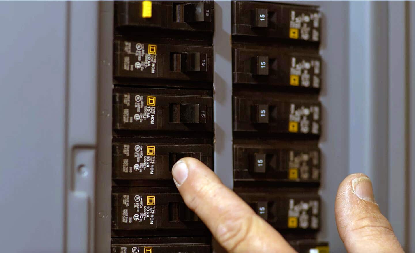 A person resets a circuit breaker in an electrical panel.
