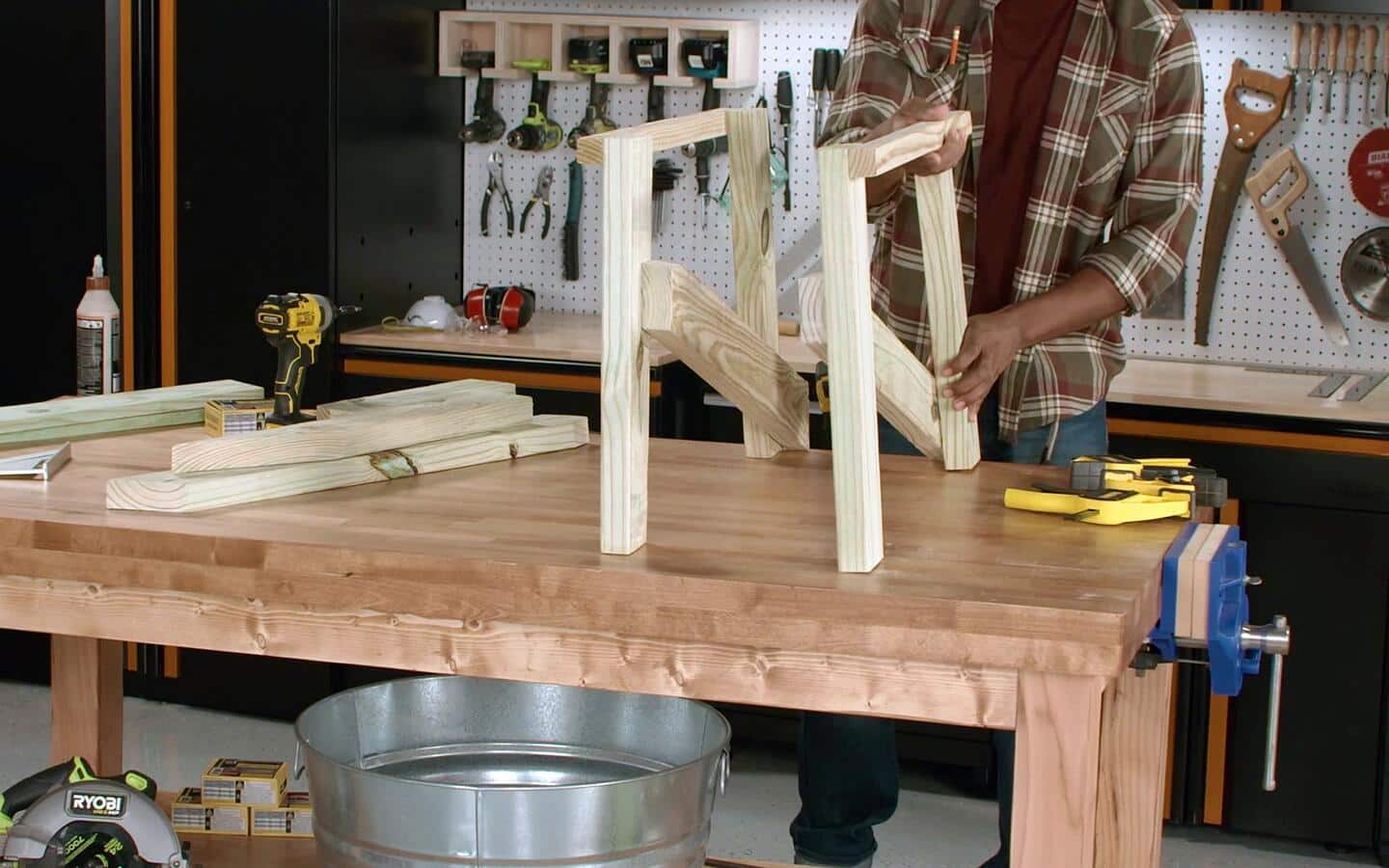 A person stands up a pair of a sofa's constructed leg supports on a worktable. A person stands up a pair of a sofa's constructed leg supports on a worktable.