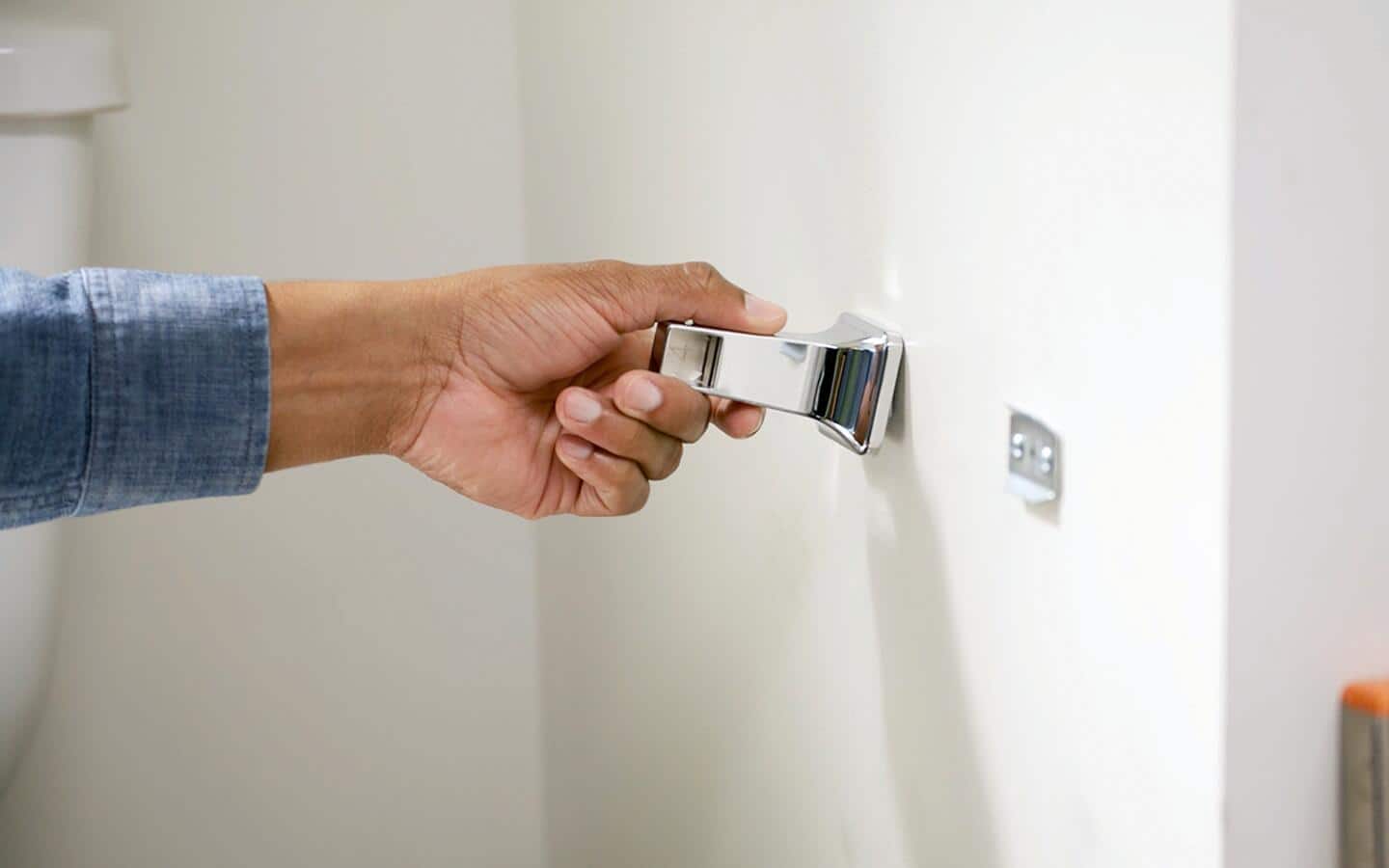 A person snaps a toilet paper holder onto the bracket.