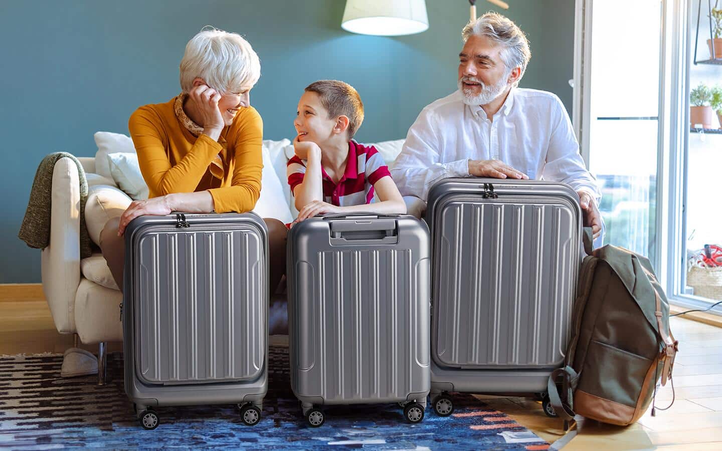 Grandparents holding luggage and sitting on a sofa with their grandson. Grandparents holding luggage and sitting on a sofa with their grandson.