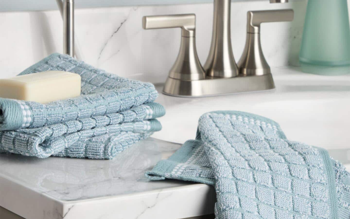 Two textured, light-green towels, with a bar of soap, on a sink. Two textured, light-green towels, with a bar of soap, on a sink.