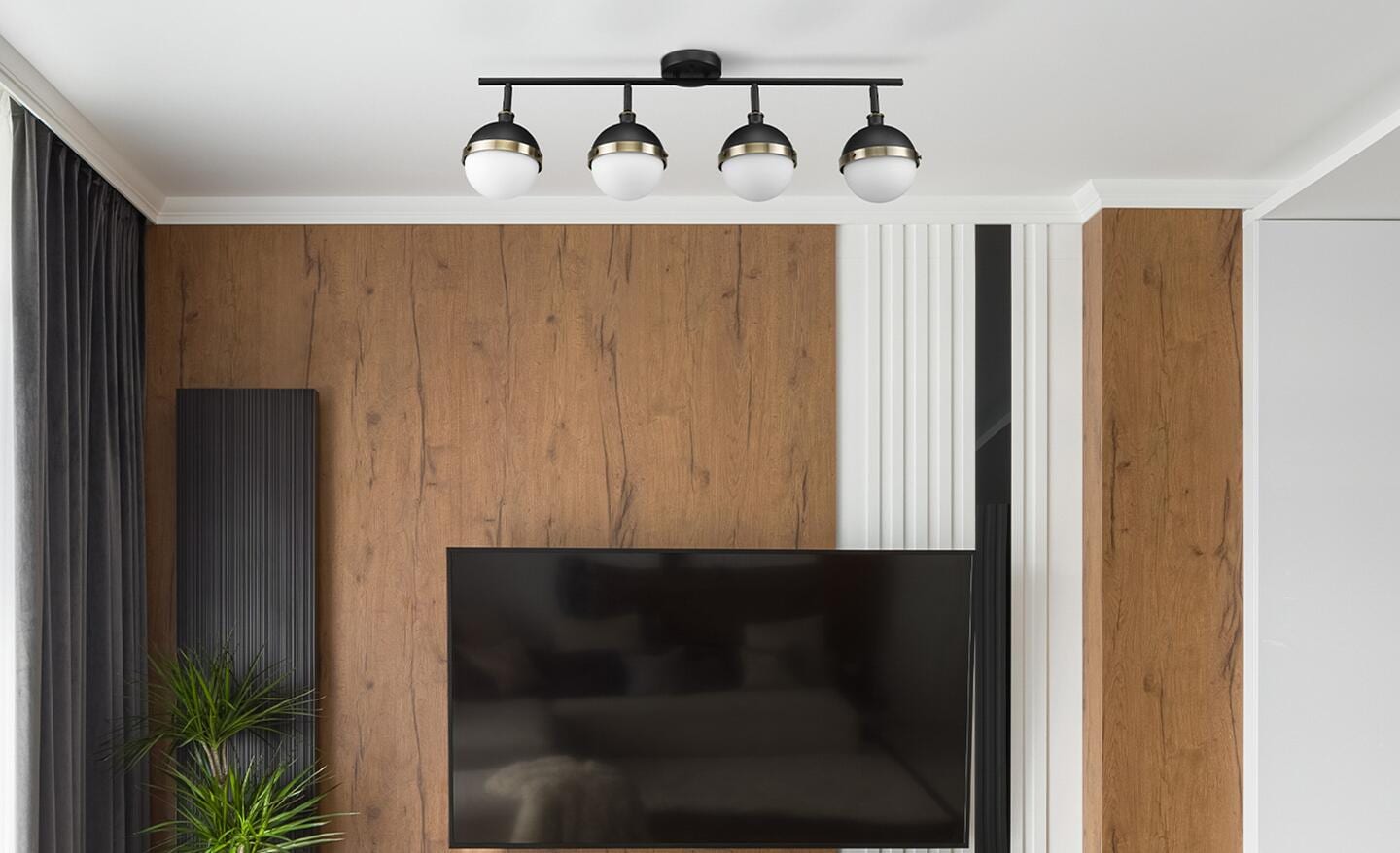 Four rounded track lights hang from a track on the ceiling of a wood-paneled room.