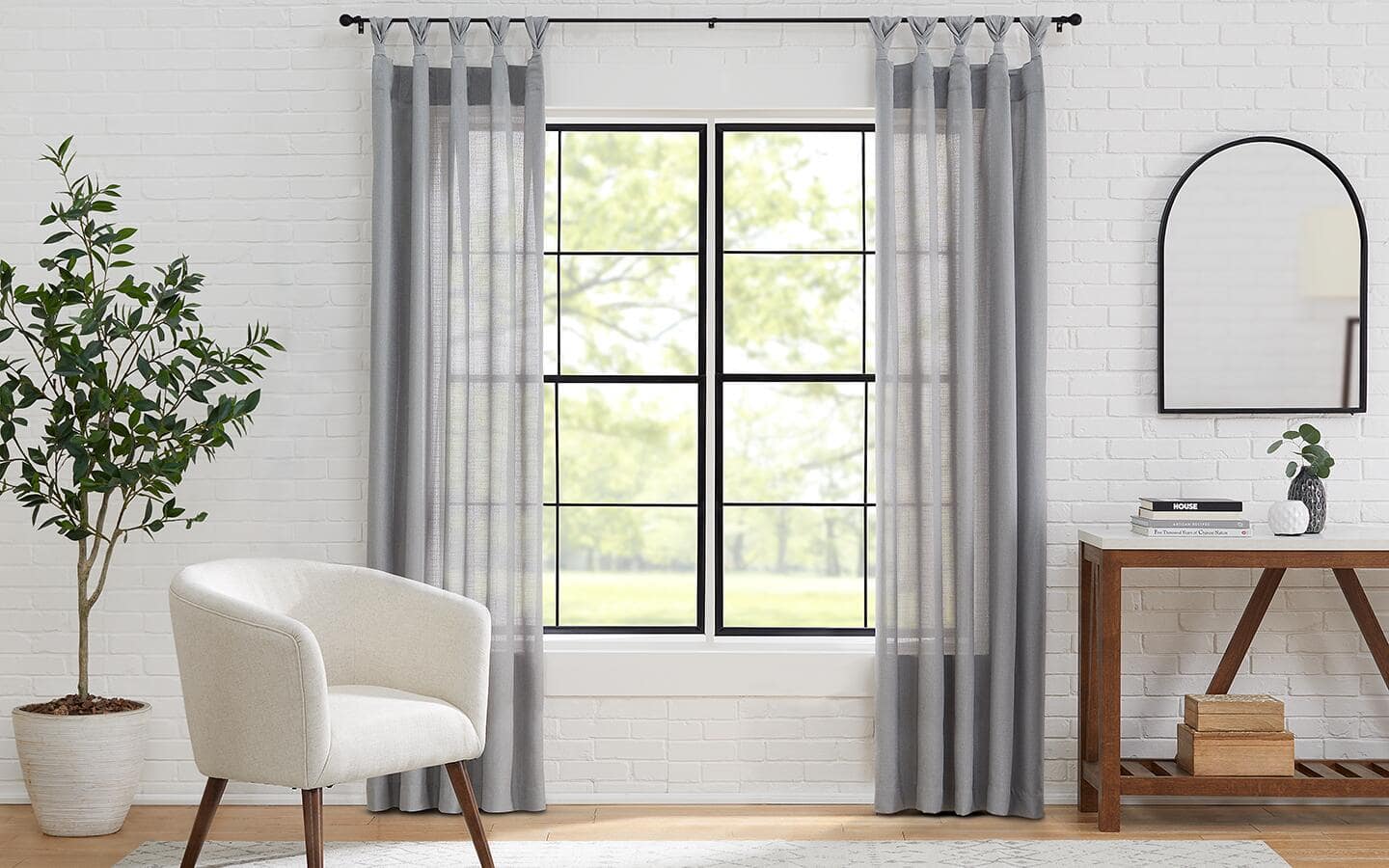A living room area with a window covered by sheer grey curtains. A living room area with a window covered by sheer grey curtains.