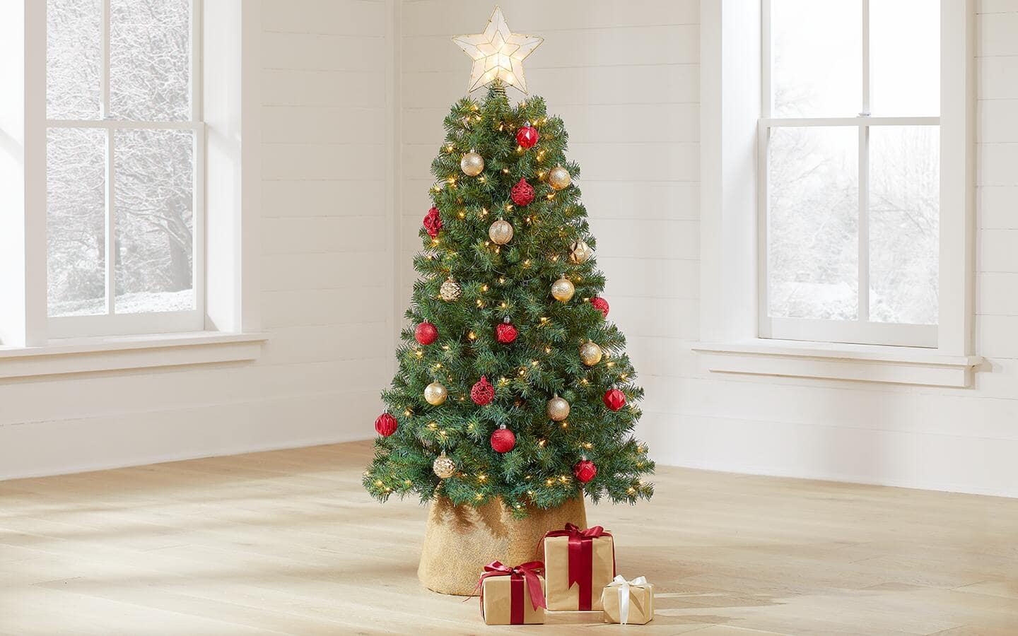 A decorated artificial Norway spruce in a holiday-themed living room.
