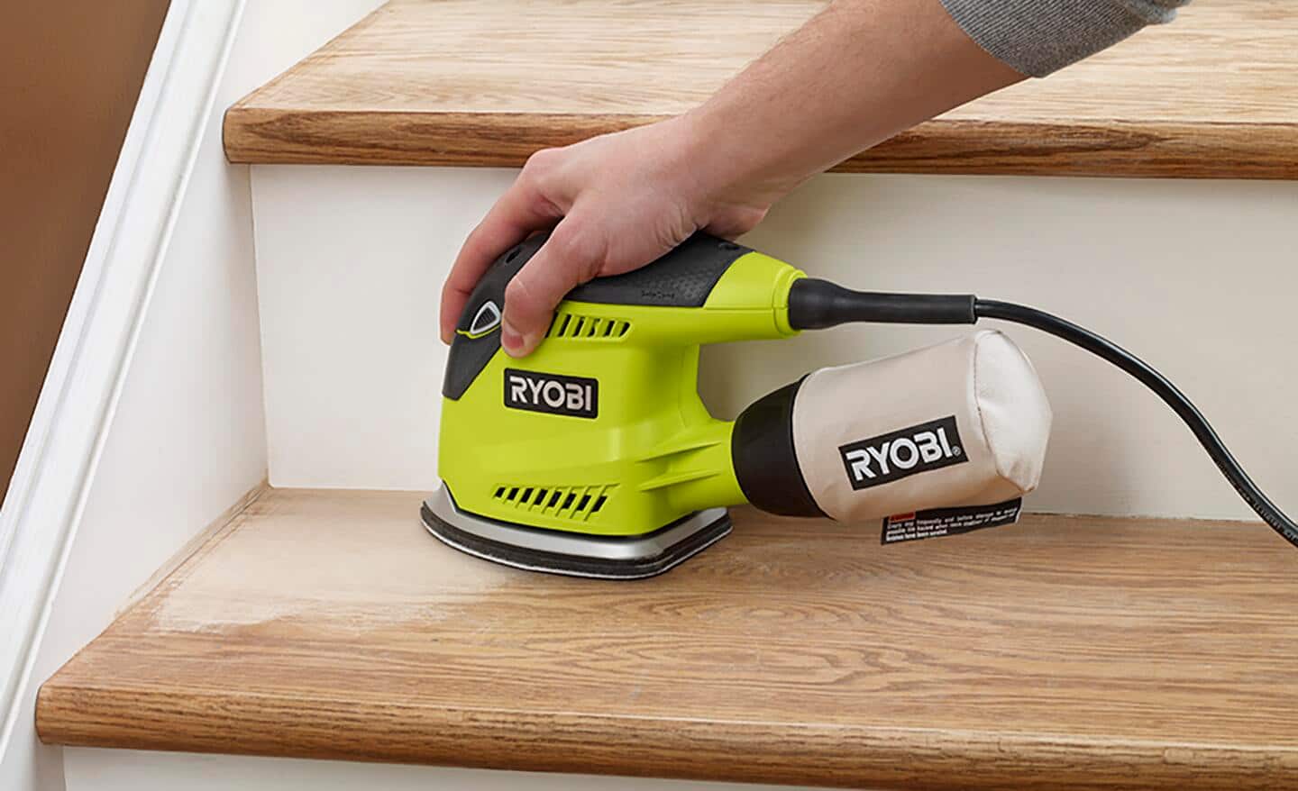 A person using an electric power sander to smooth stairs.