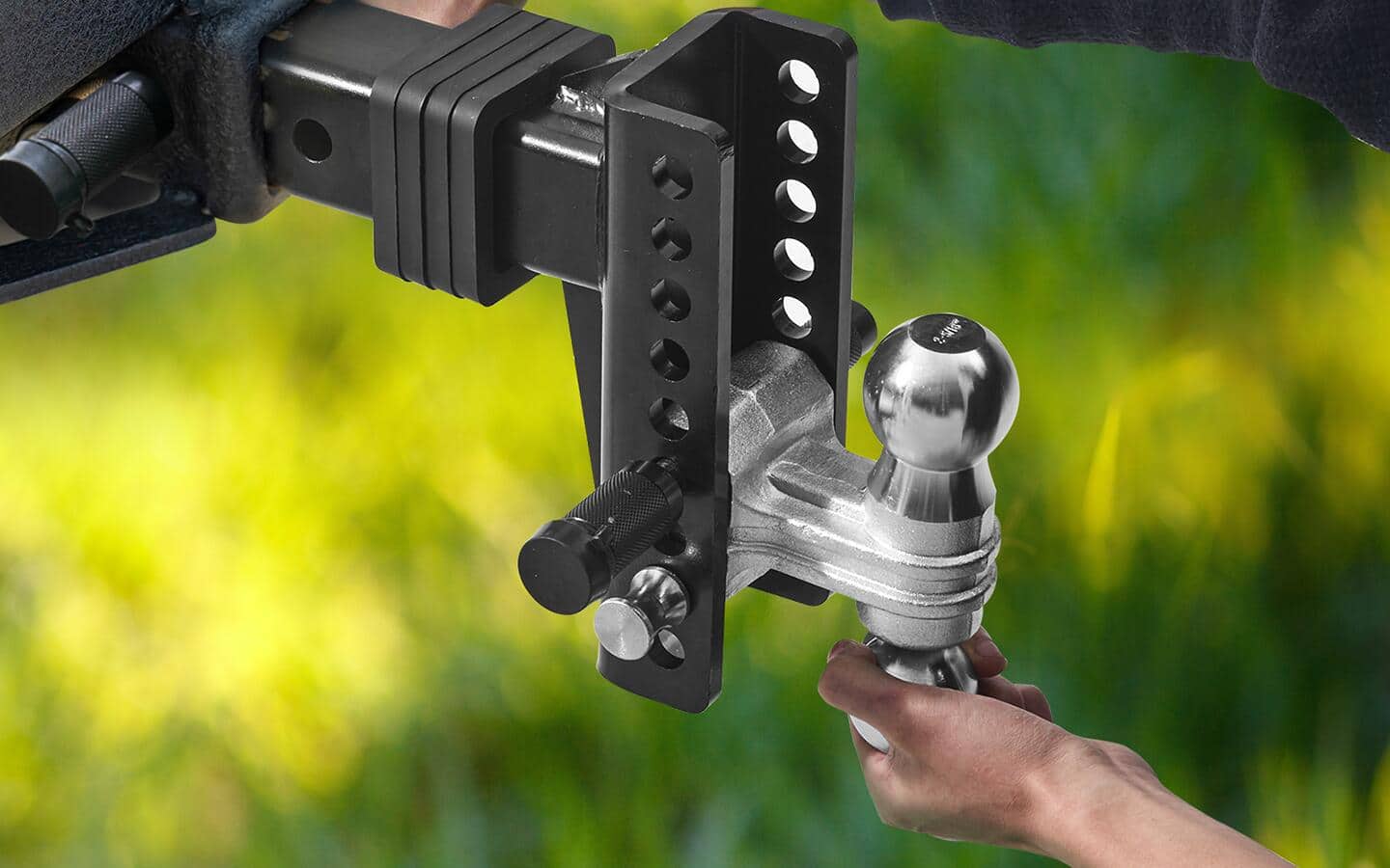 Someone grasping a silver hitch ball connected to a black ball mount.