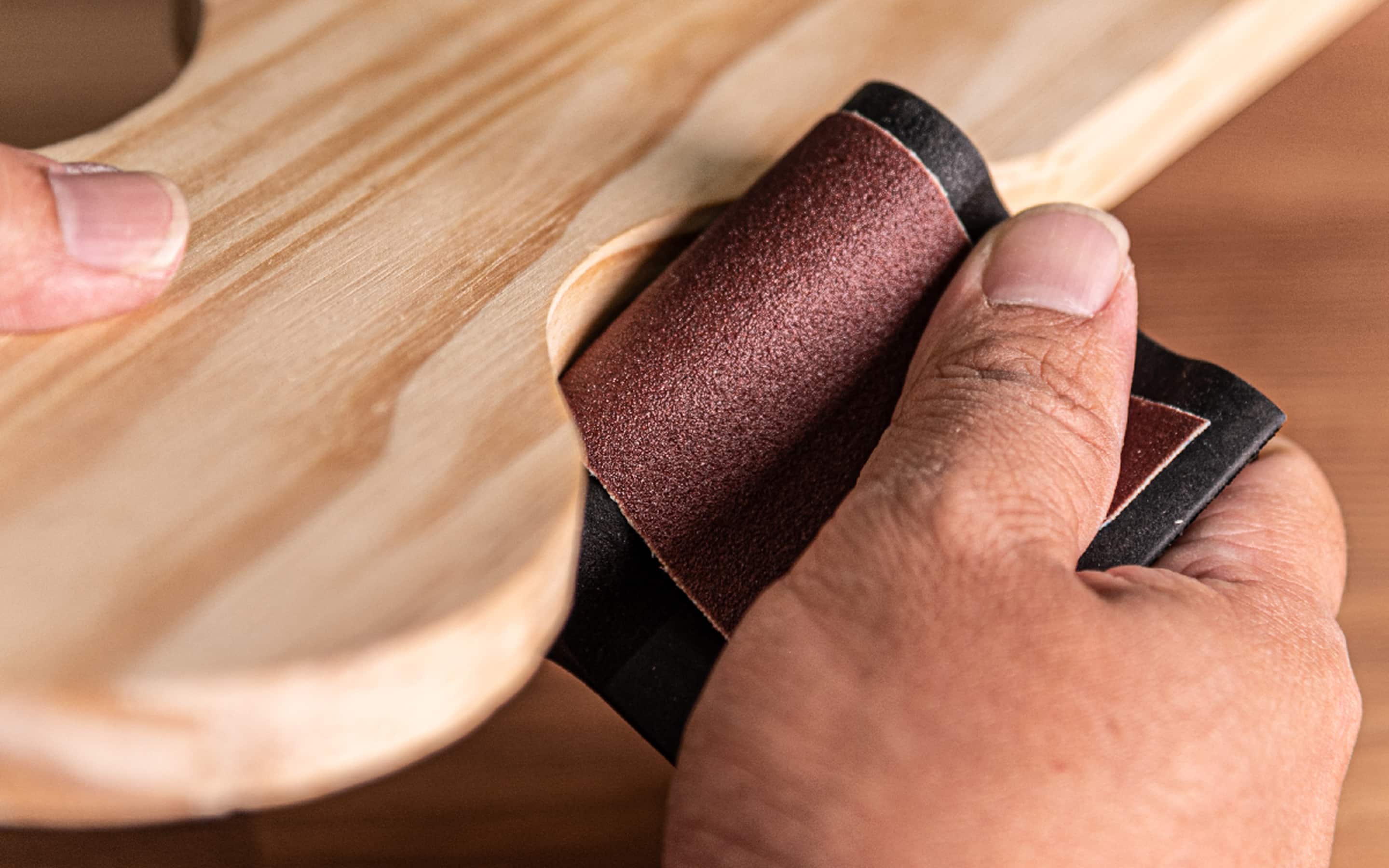 A person sanding wood with aluminum oxide sandpaper.