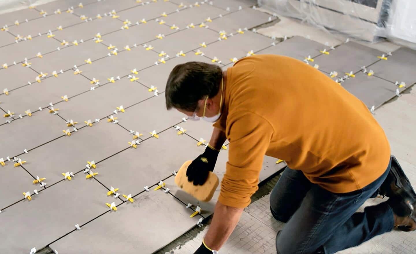 A person cleans newly placed tiles with a sponge.
