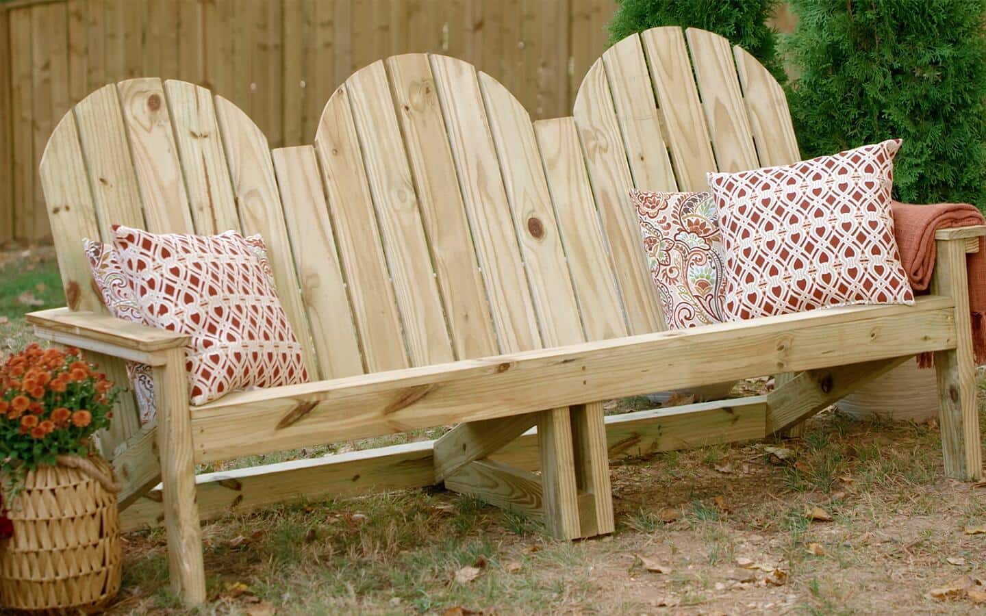 An outdoor sofa with red-and-white throw pillows in a backyard. An outdoor sofa with red-and-white throw pillows in a backyard.