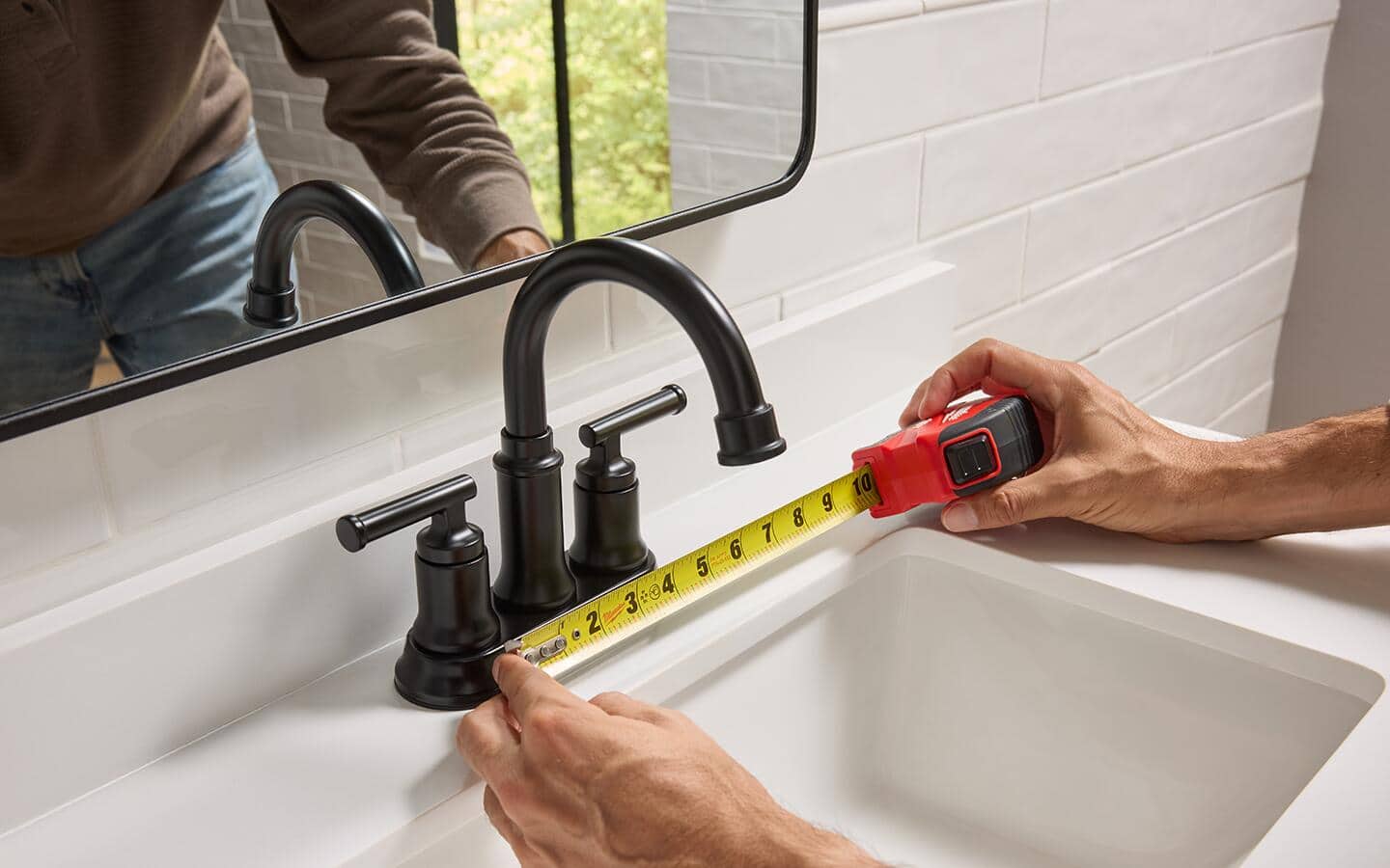 Using a tape measure to verify the width of a 4 inch centerset bathroom faucet.