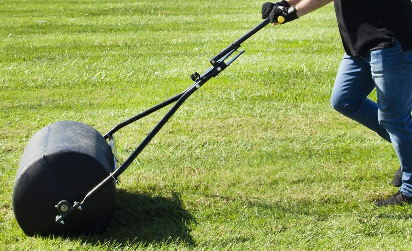 Someone using a roller to push new sod into the ground.