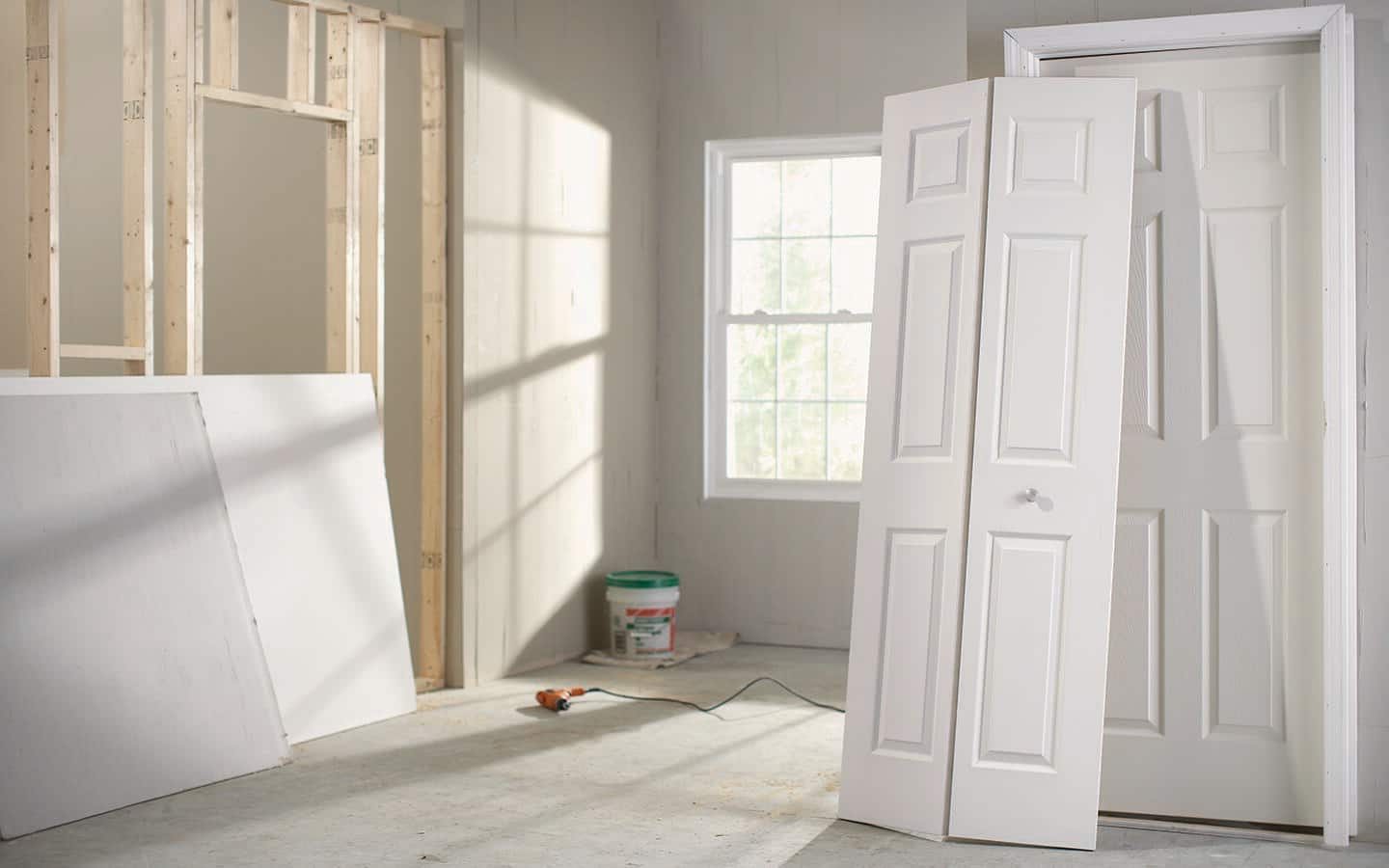 A new, white bifold door propped up and ready for installation. A new, white bifold door propped up and ready for installation.