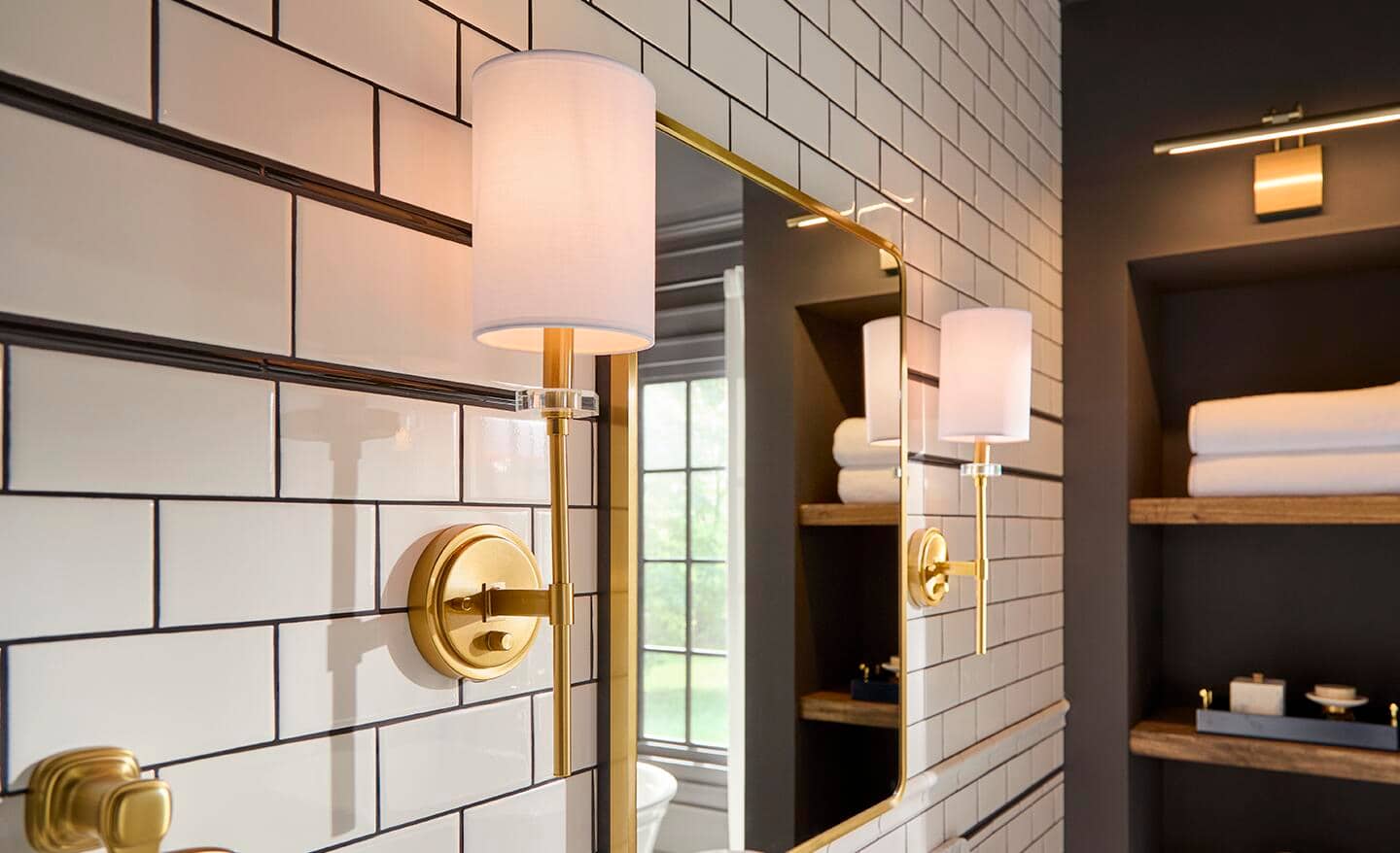 Gold sconce lights installed on a subway tile wall.