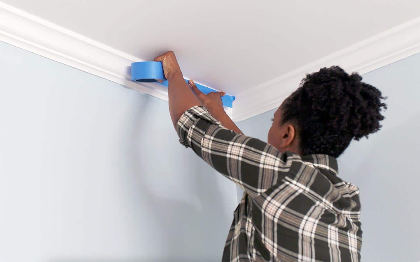 A person applying painters' tape to protect themselves and the room. A person applying painters' tape to protect themselves and the room.