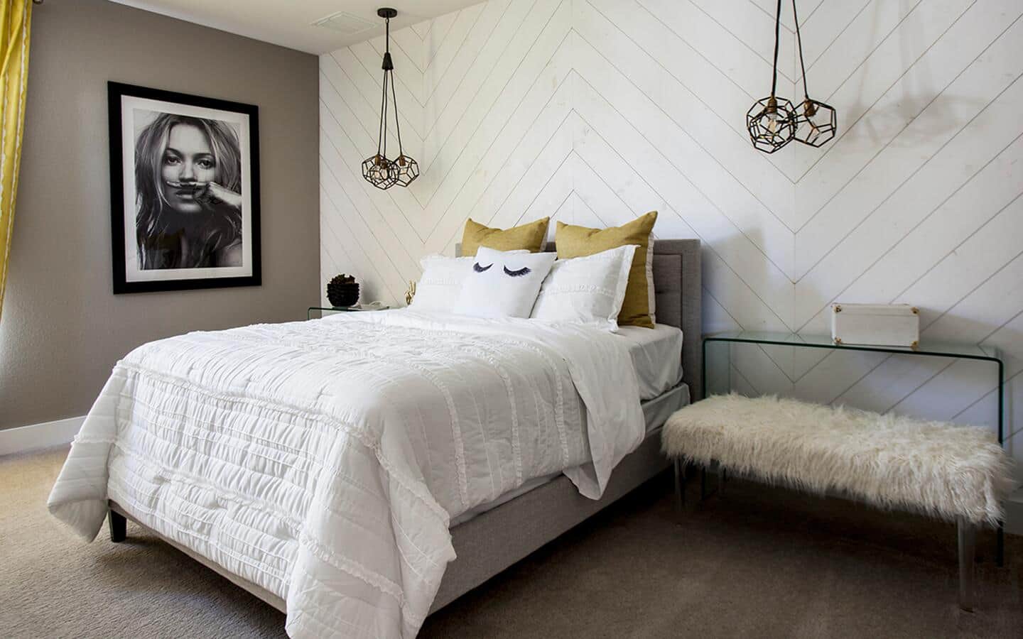 A bedroom with one wallpapered wall and another painted with hung artwork.