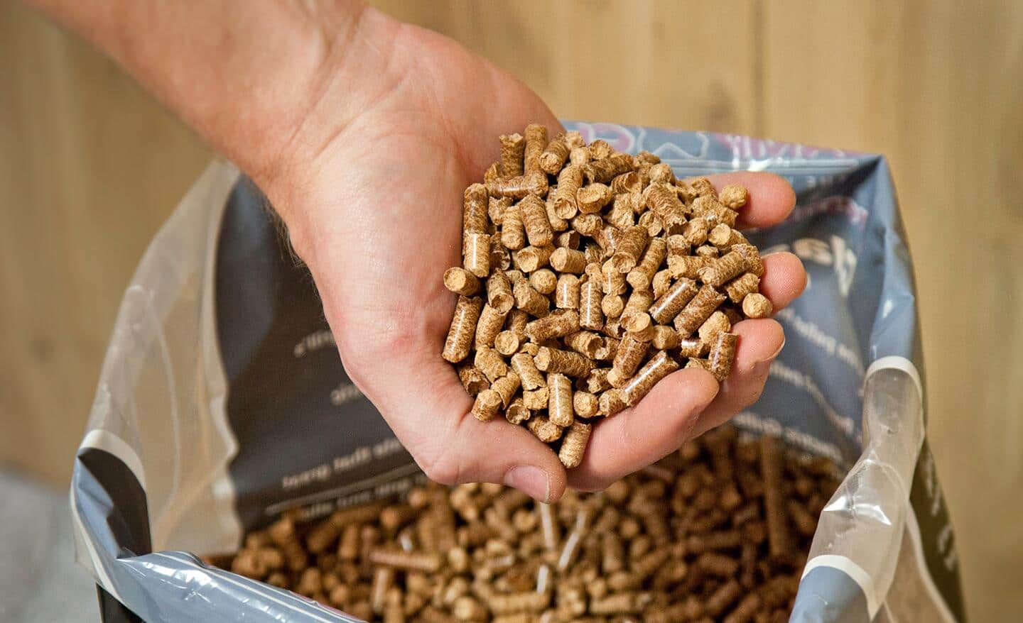 A person holding wood pellets that serve as fuel for a pellet grill.