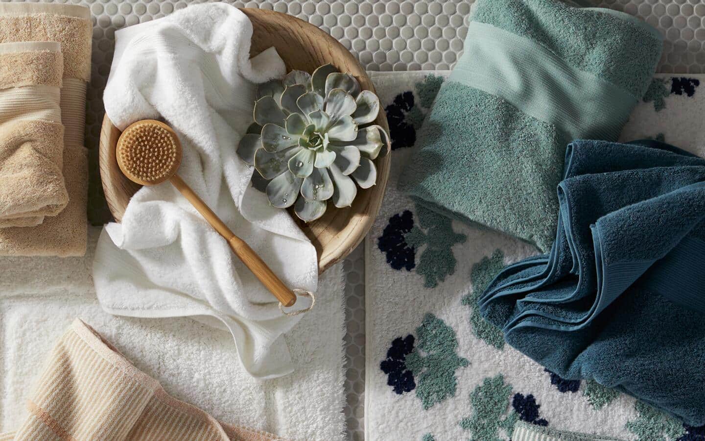 Egyptian cotton towels, in different colors, next to a bowl with a bath brush. Egyptian cotton towels, in different colors, next to a bowl with a bath brush.