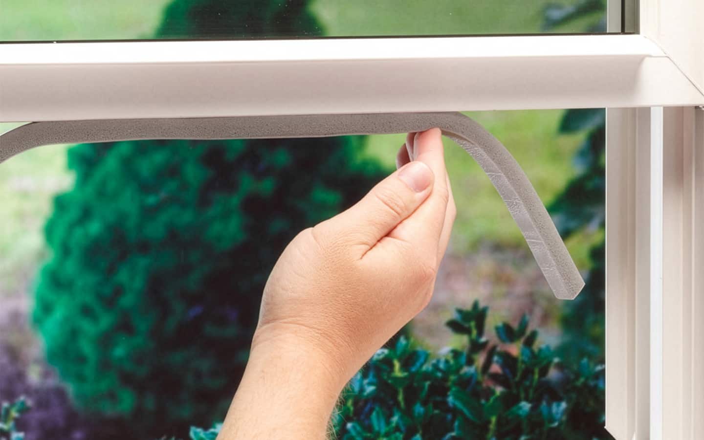 Someone adding foam-backed weatherproofing to casement windows.
