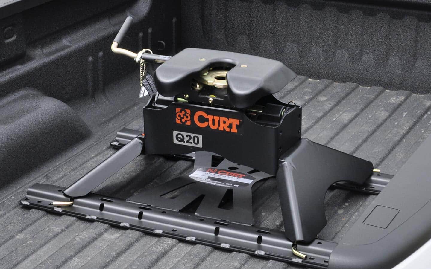 A 5th wheel hitch connected to the bed of a grey truck.