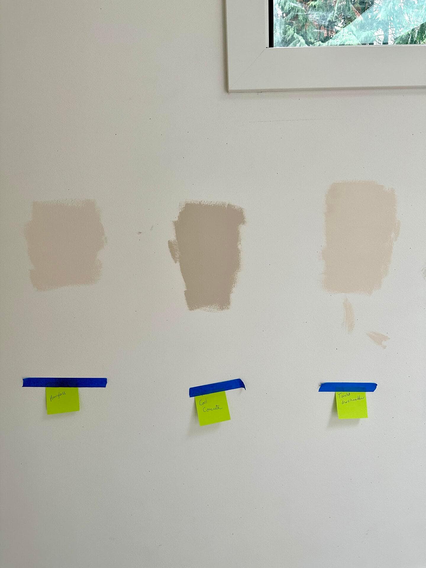 Three paint colors tested on a wall, with yellow sticky notes below for identification