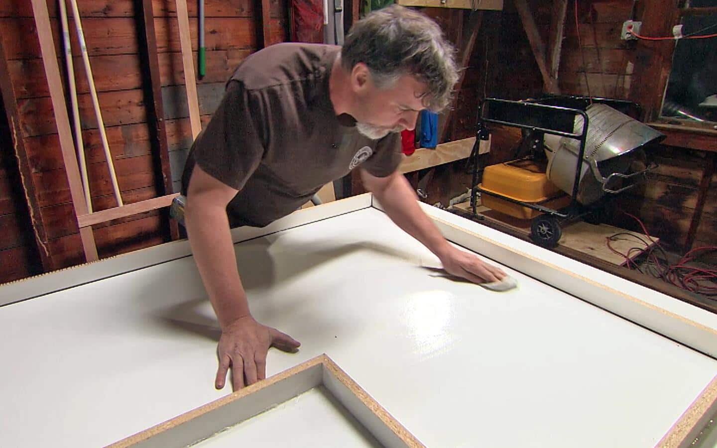 A person wipes the base of a concrete countertop form. A person wipes the base of a concrete countertop form.