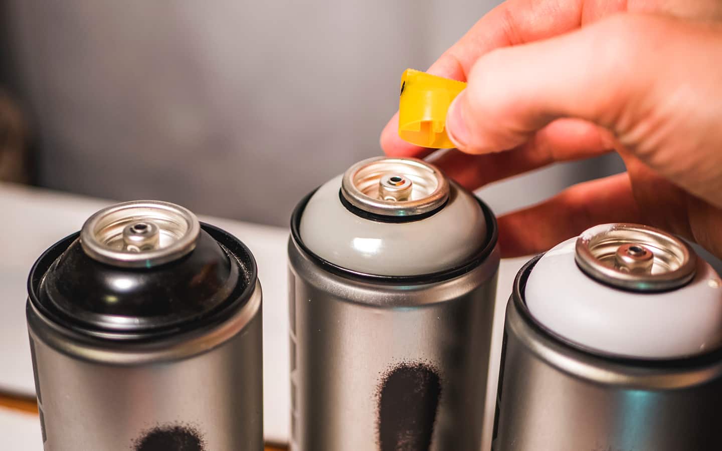 A person removing the nozzle from a can of spray paint.