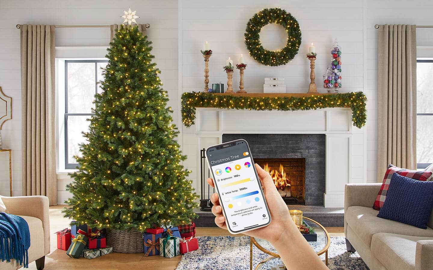 Someone holding up a smartphone to an artificial Christmas tree in a holiday living room.