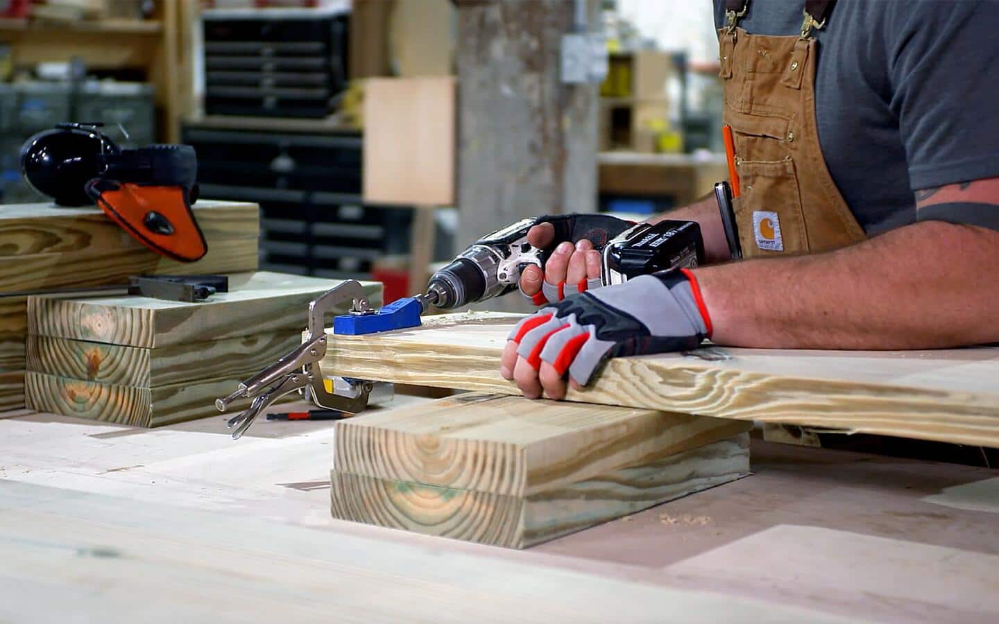A gloved individual drills into a board to create pocket holes.